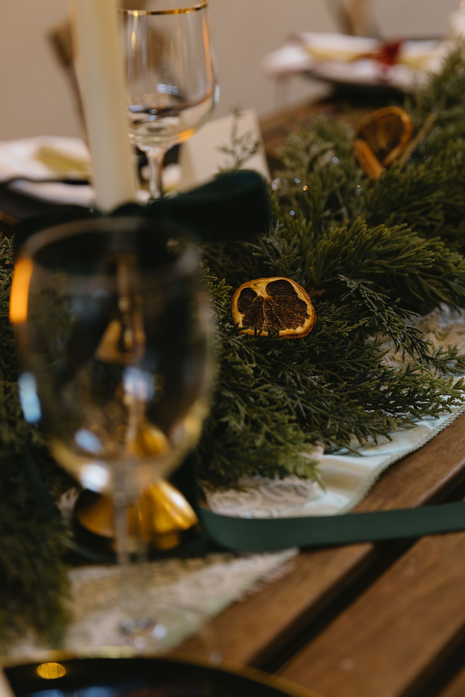 Wedding reception table decorated with fresh pine branches and glowing candlelight.