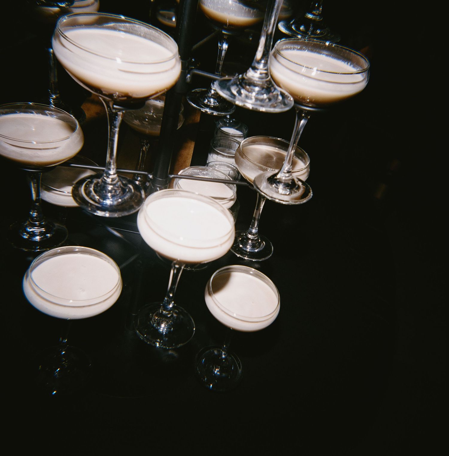 Multiple champagne coupes arranged in dramatic lighting at an event.