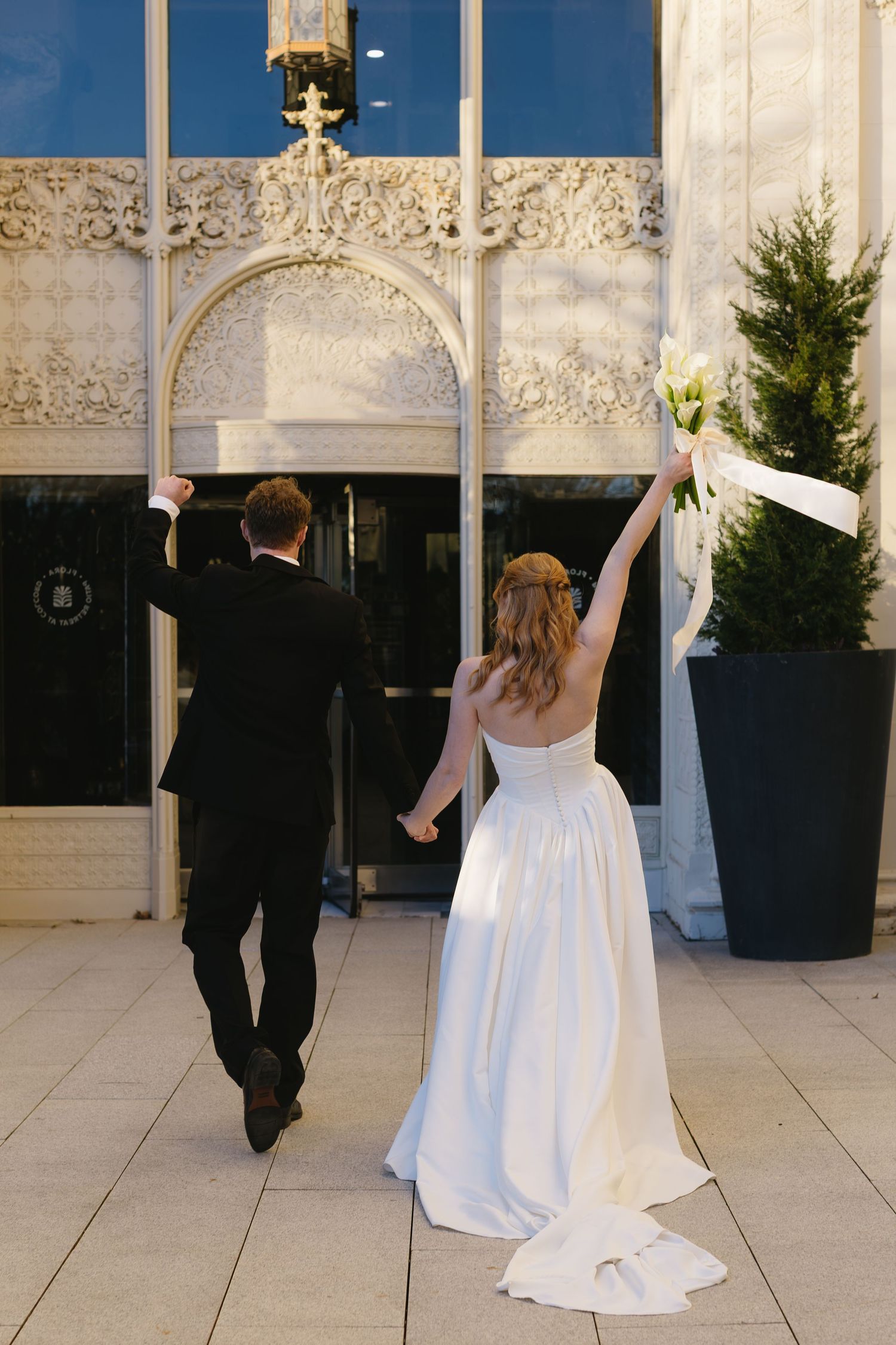 A bride in a flowing white gown twirls on a tiled floor with decorative architectural details in the background.