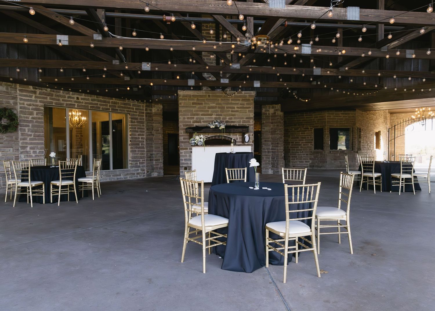 Reception venue with string lights and empty tables set up for a wedding celebration.