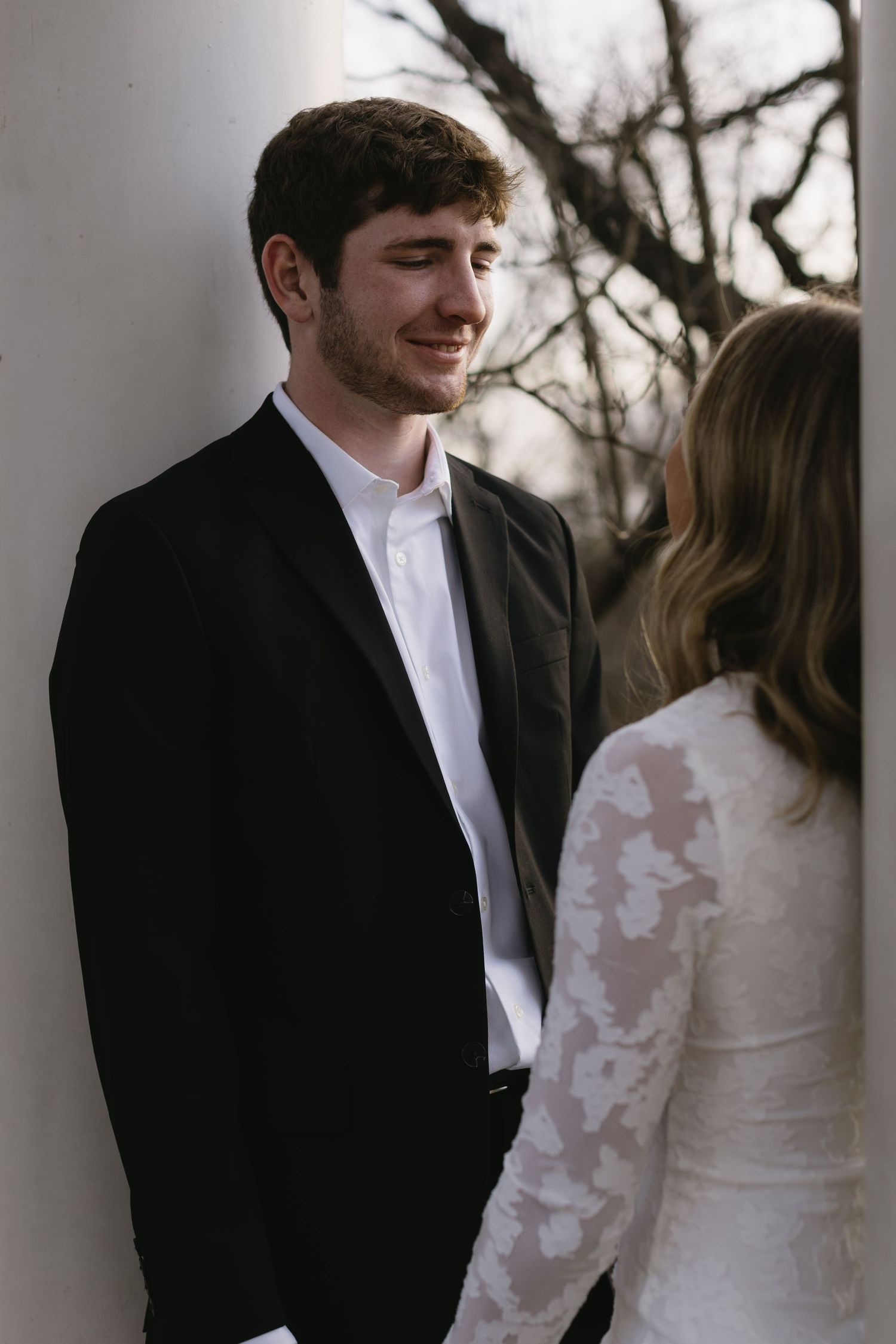 Romantic couple in black and white formal wear share an intimate moment outdoors.