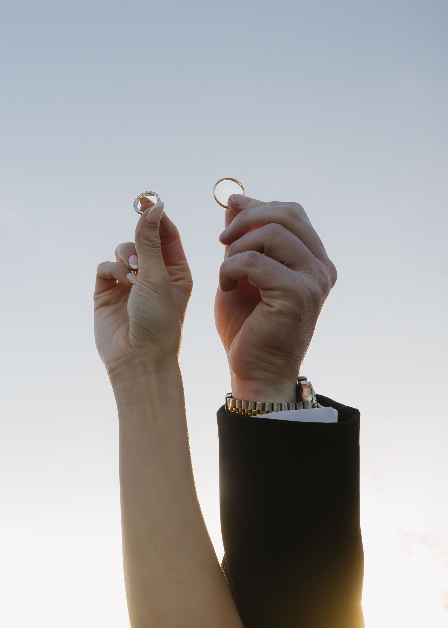Two hands displaying wedding rings against a light blue background in a series of close-up shots.
