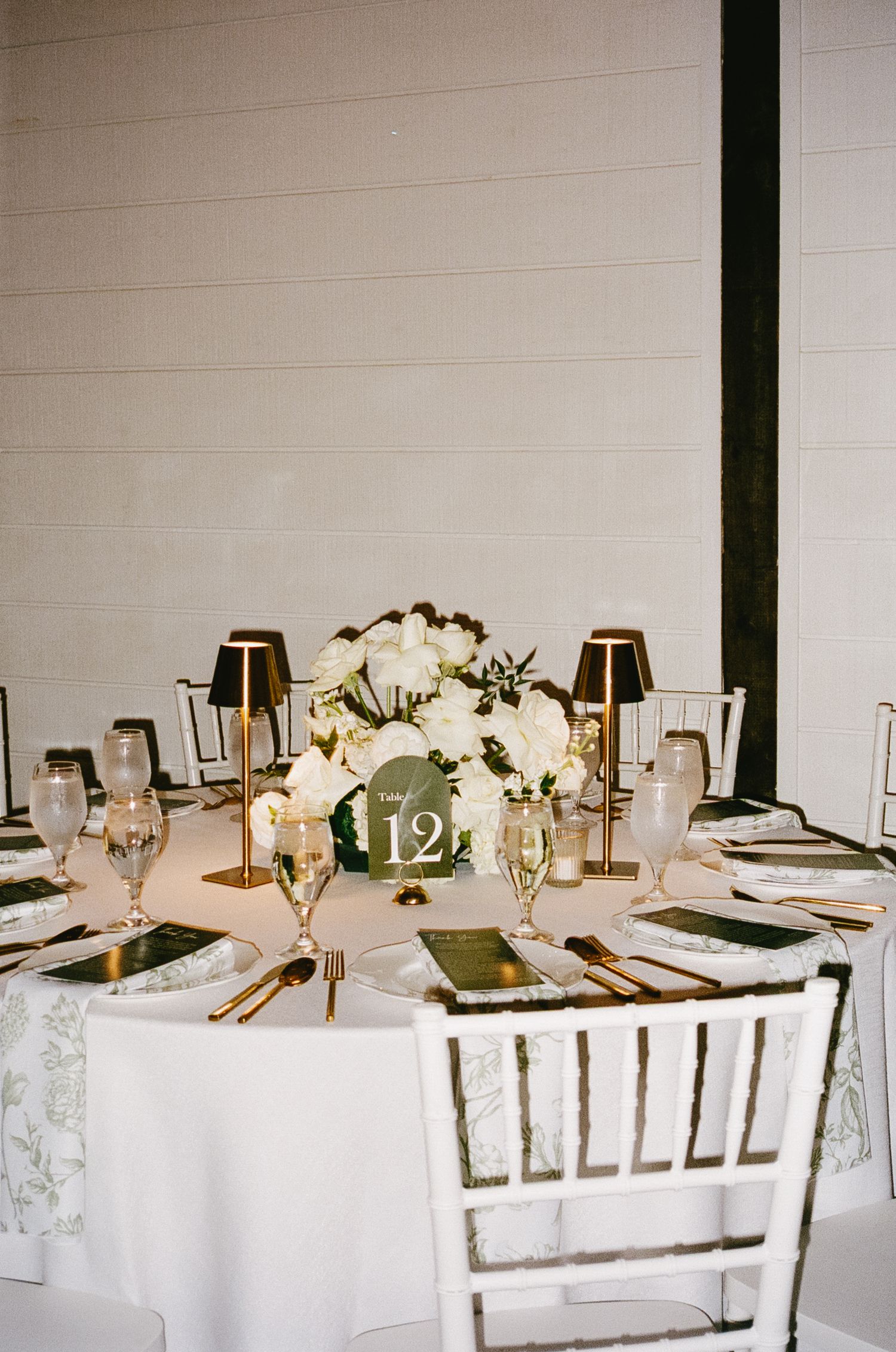 Elegant wedding reception table with white floral centerpieces and gold accents.