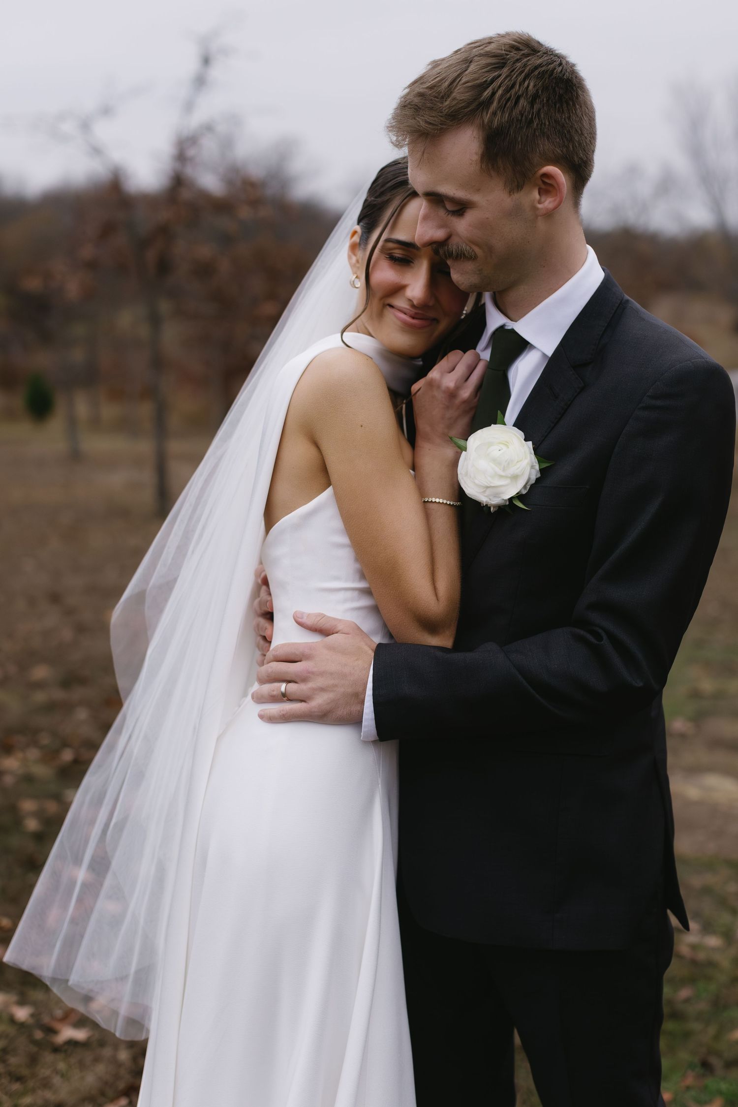 Wedding couple shares tender moments in outdoor setting with bride in flowing white dress and veil.