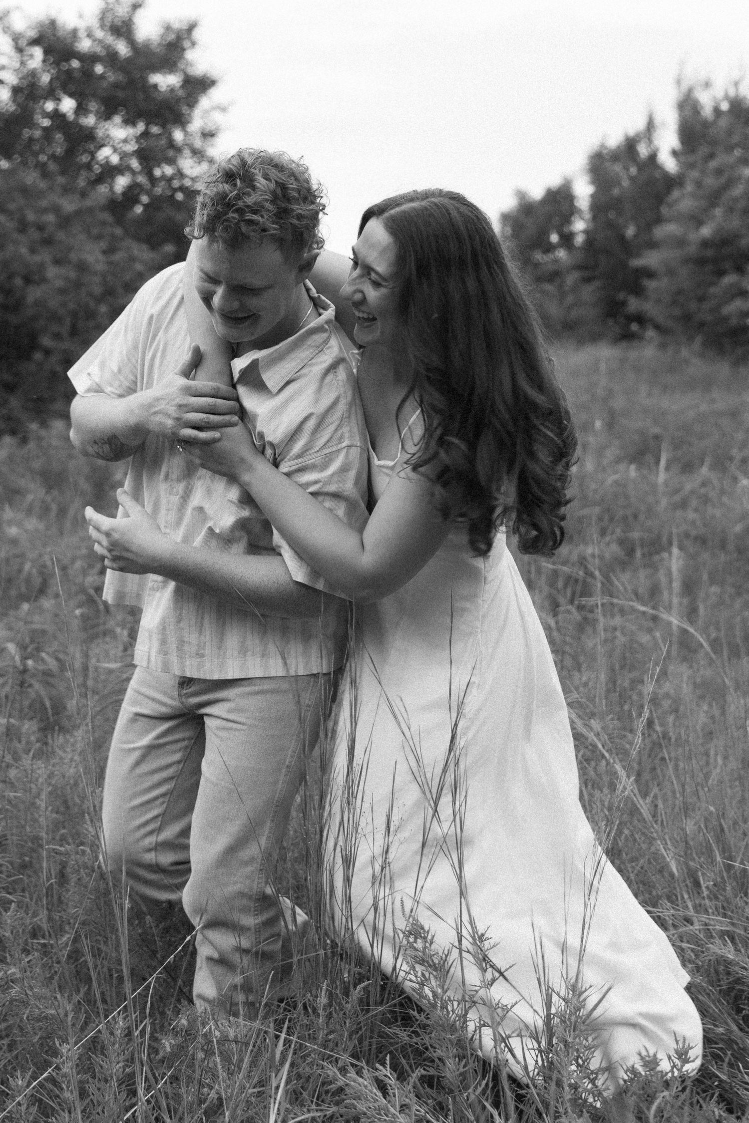 Loving couple sharing joyful moments in a field of tall grass on a sunny day.