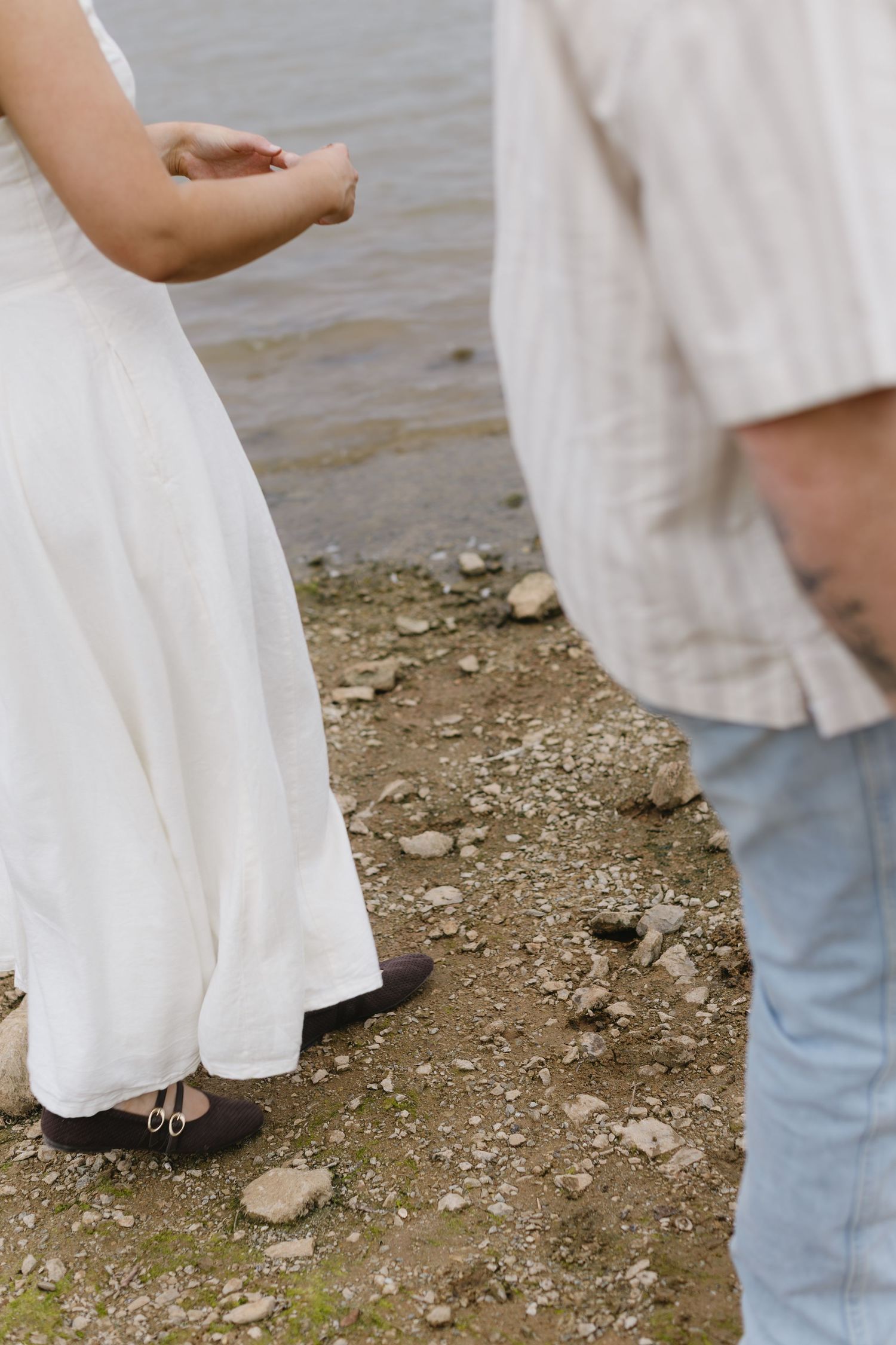 Low angle shots showing feet and hands of a couple standing on rocky shoreline.