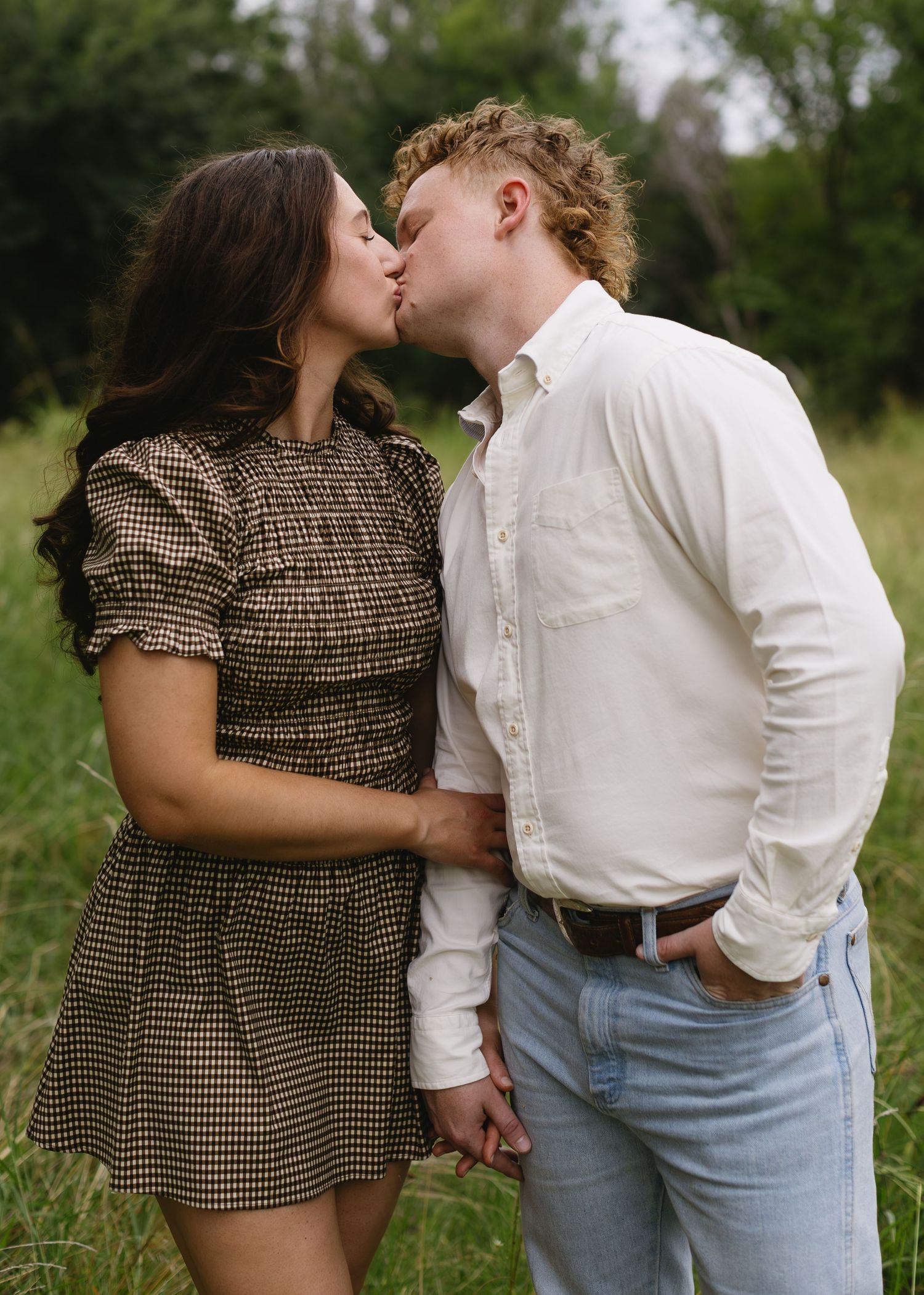 Romantic couple in vintage-inspired outfits sharing intimate moments in a meadow.