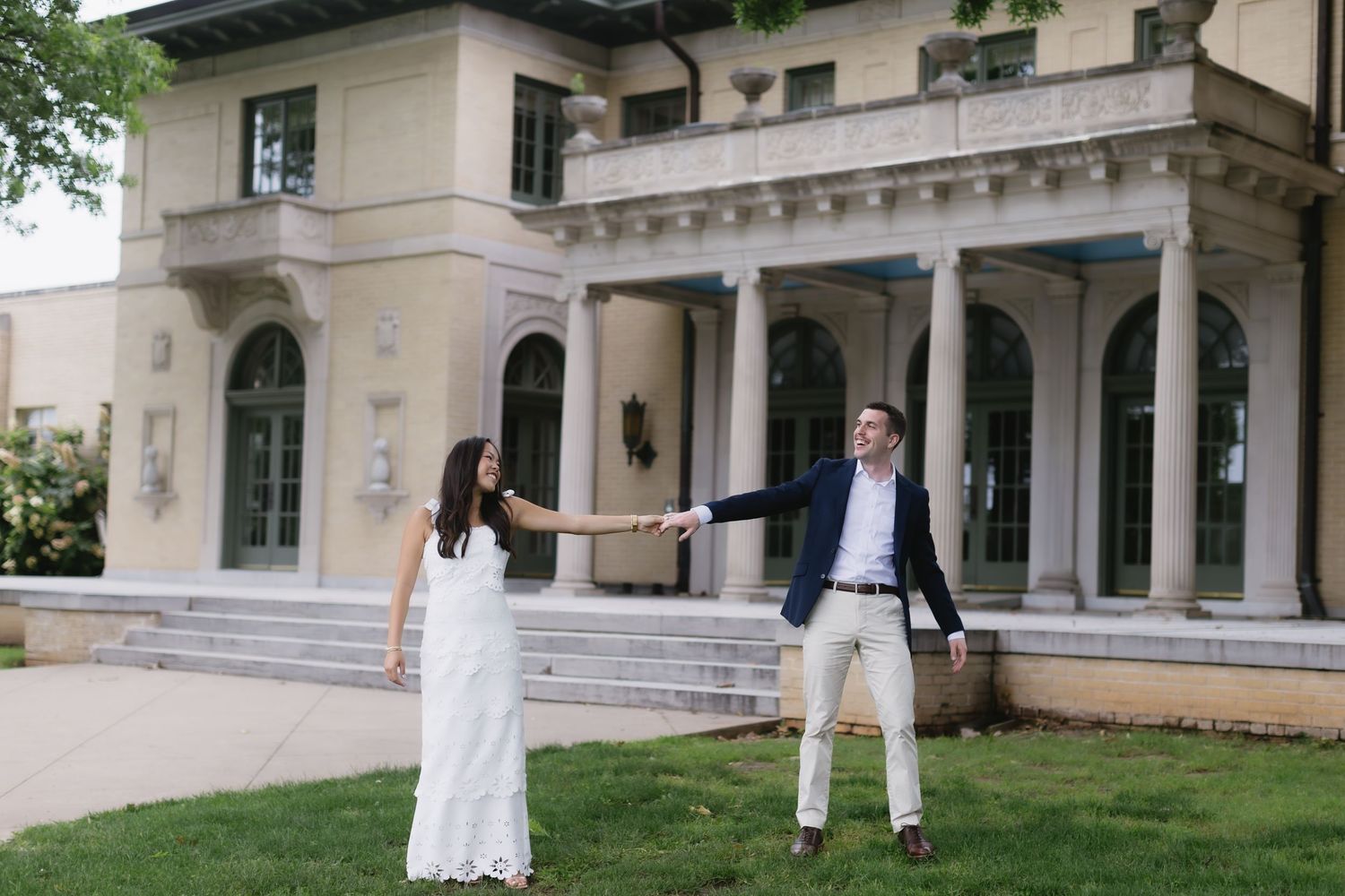 Elegant engagement photos taken in front of a grand white colonial building with columns.