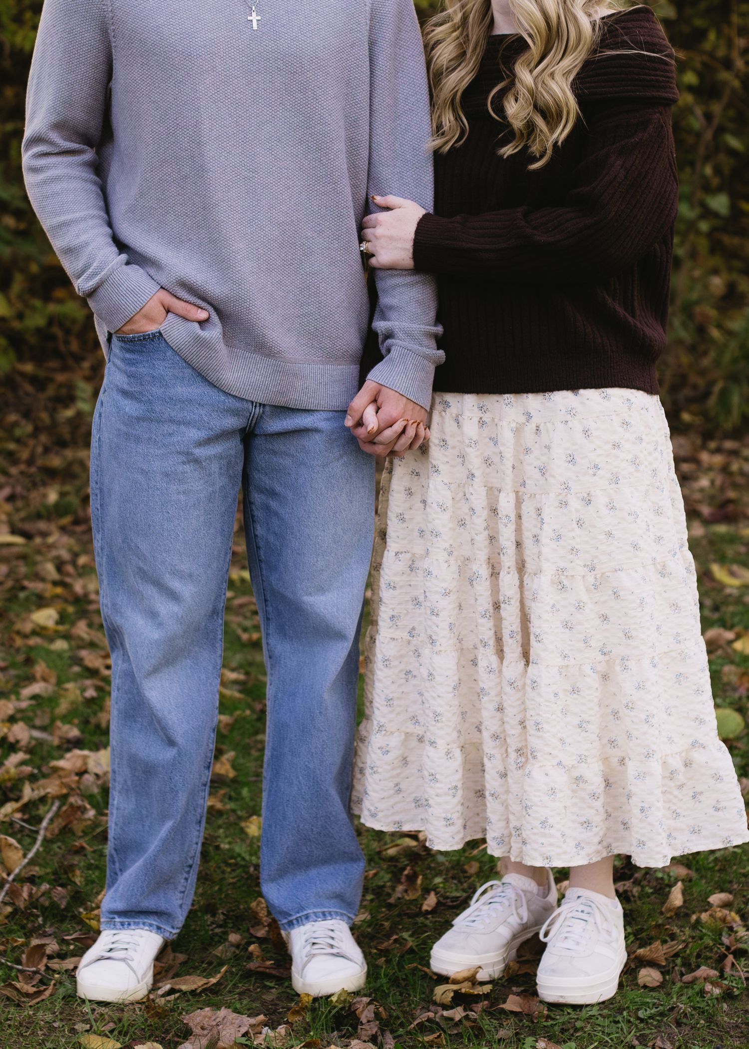 Couple in casual wear standing together on fallen autumn leaves.
