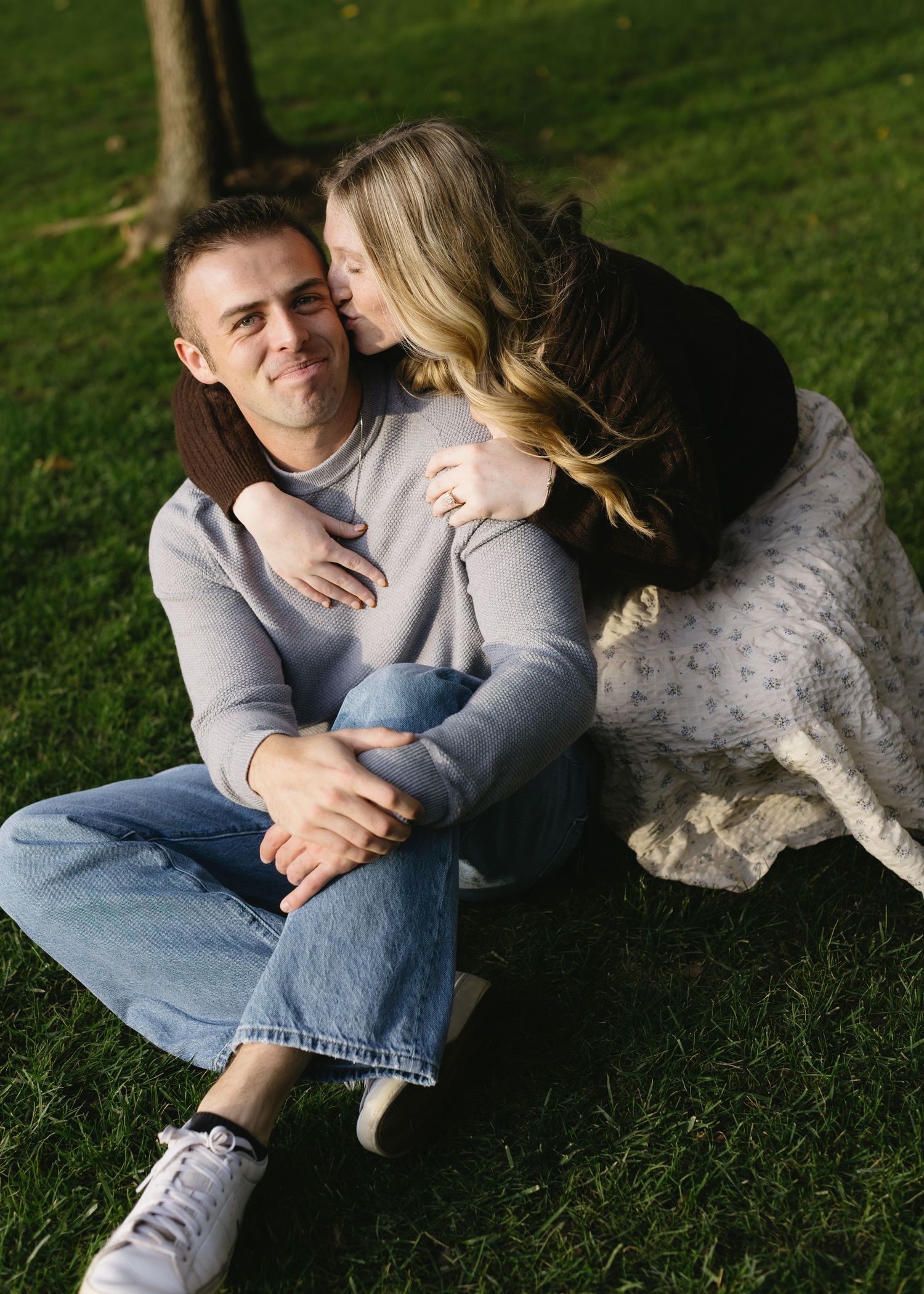 A couple lounges on grass during a romantic outdoor photoshoot.