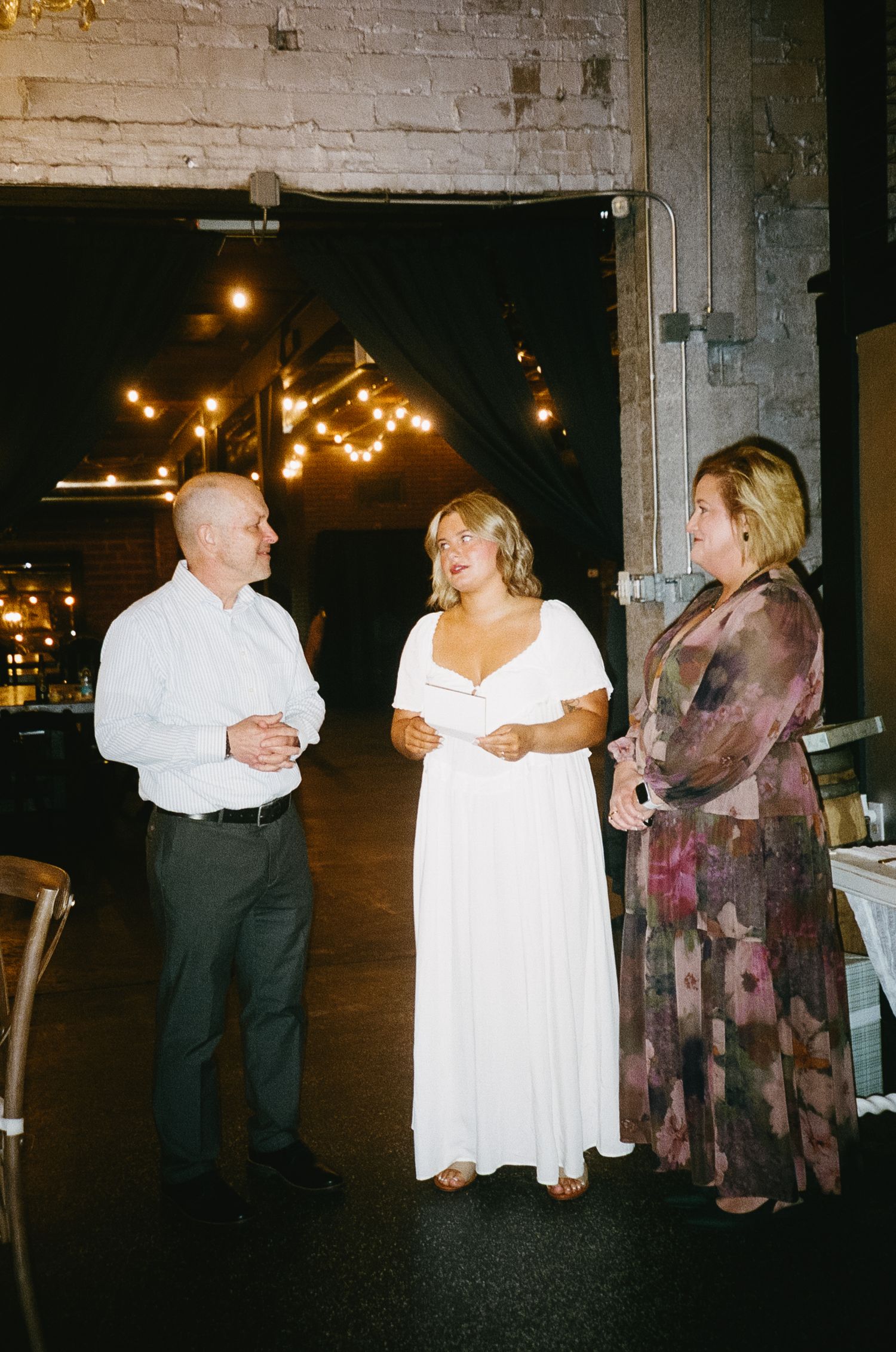 People in formal attire having conversation at evening wedding reception.