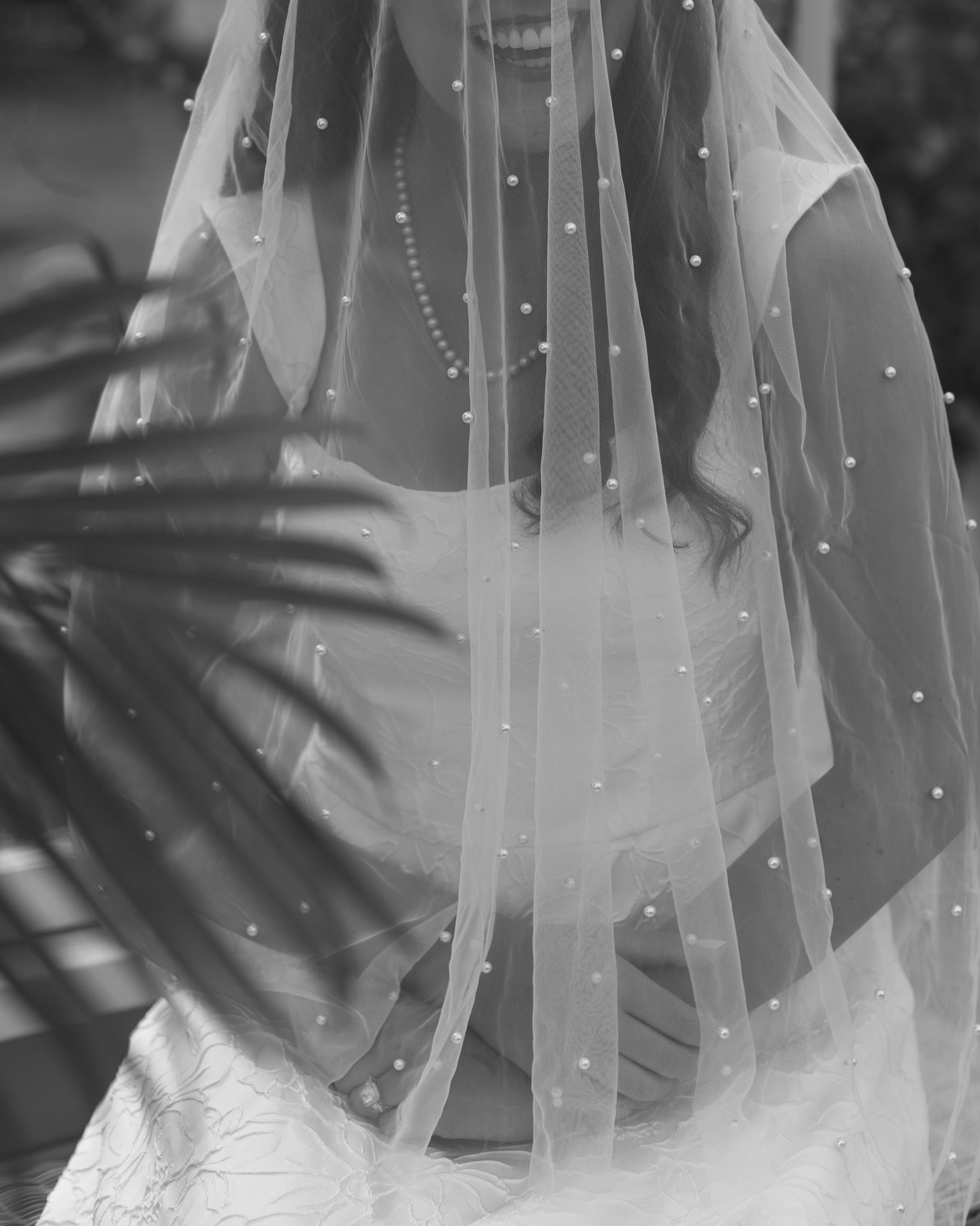 Close up view of a transparent bridal veil with delicate pearl beading details in black and white.