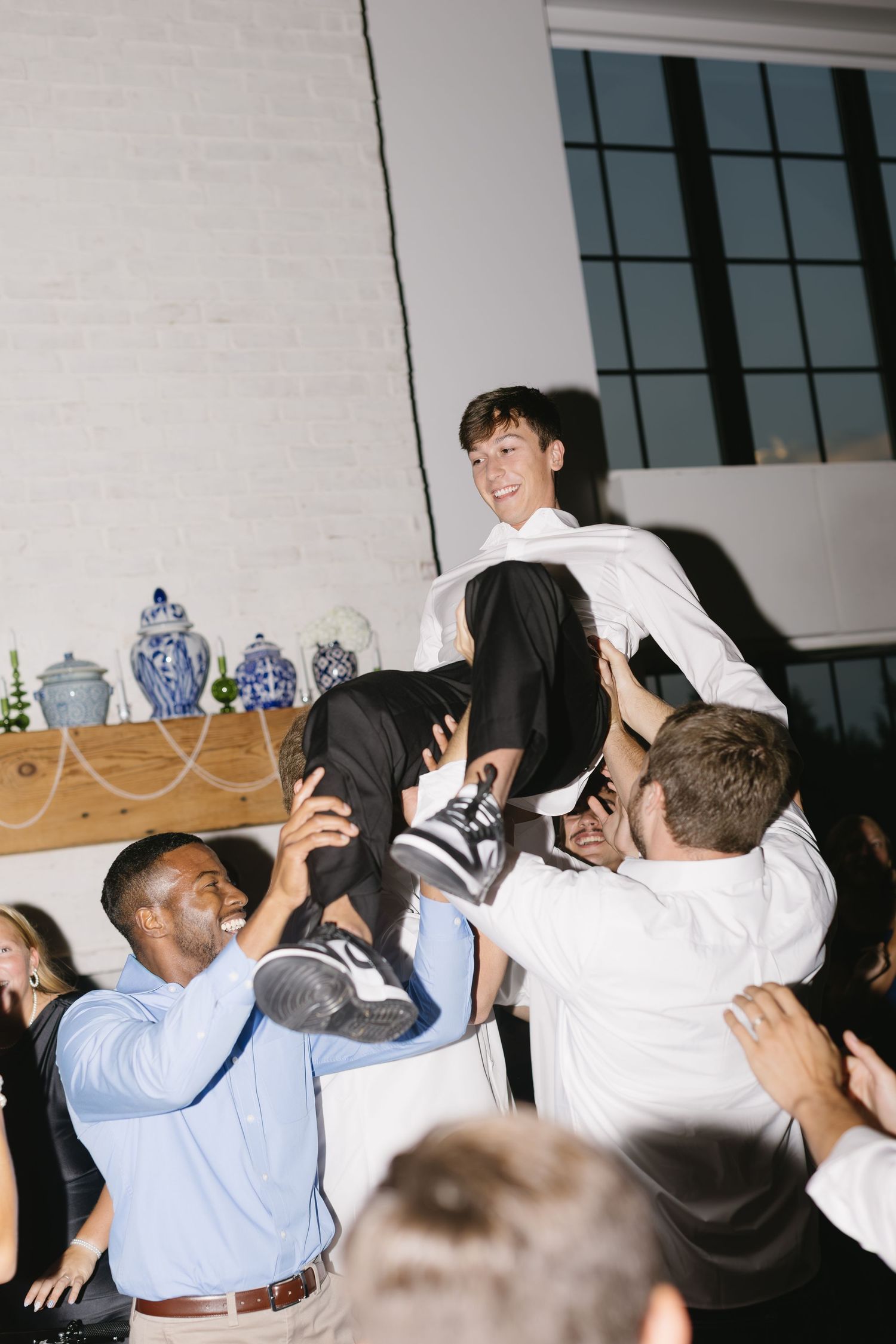 Energetic crowd of wedding guests dancing and celebrating at indoor reception.