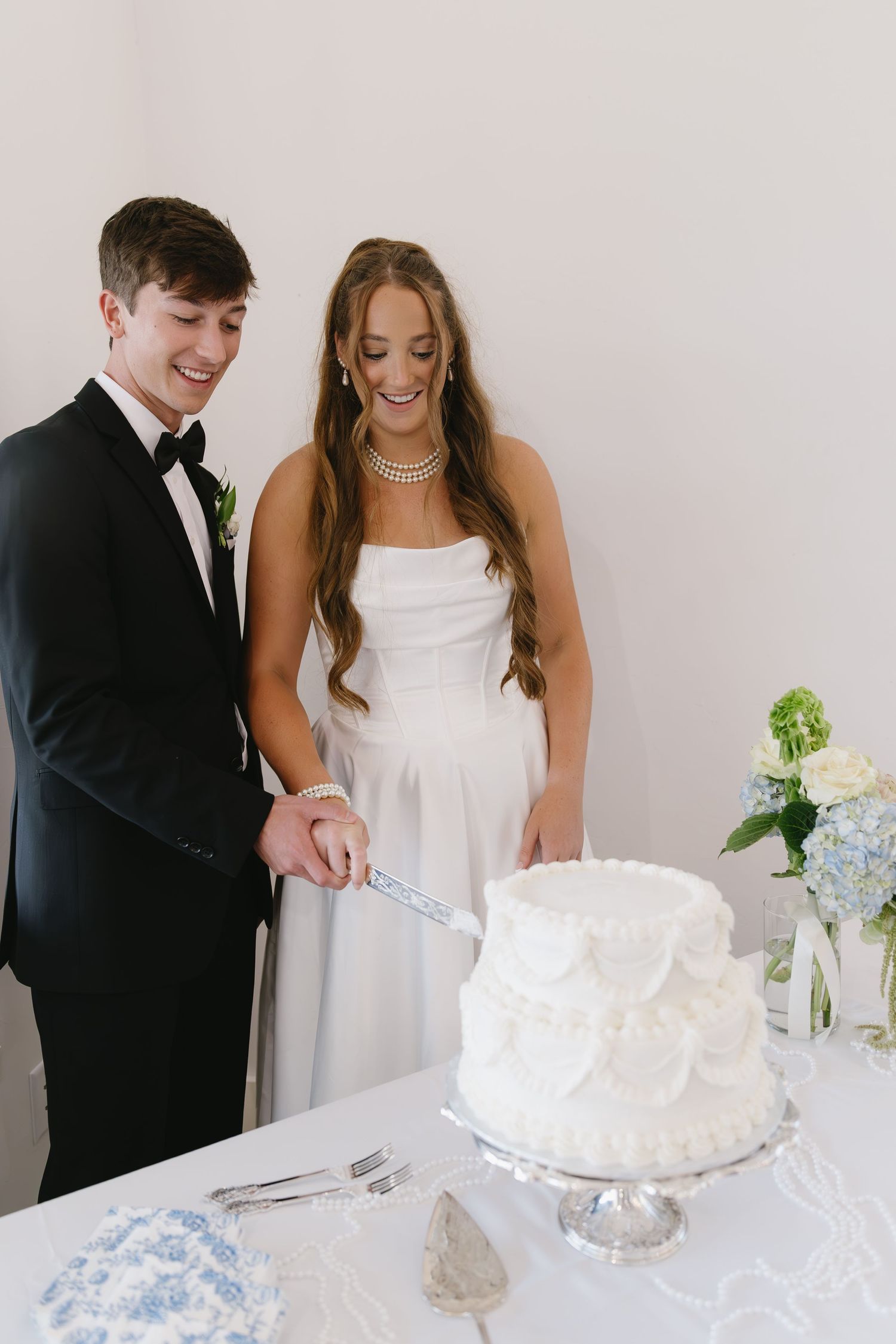A couple cutting their elegant white wedding cake together at their reception.