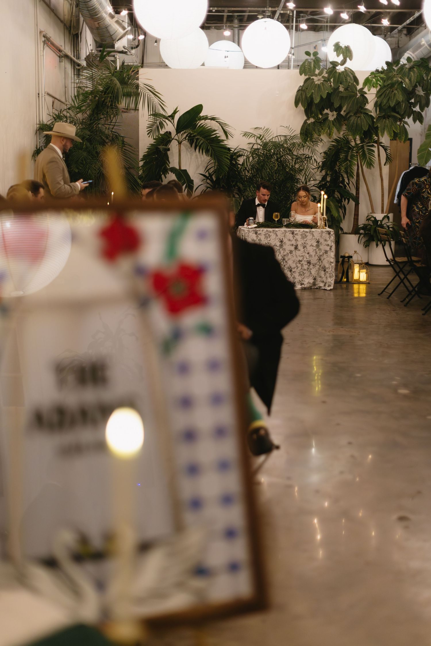 Indoor wedding venue with string lights and tropical plants creating an ambient atmosphere.