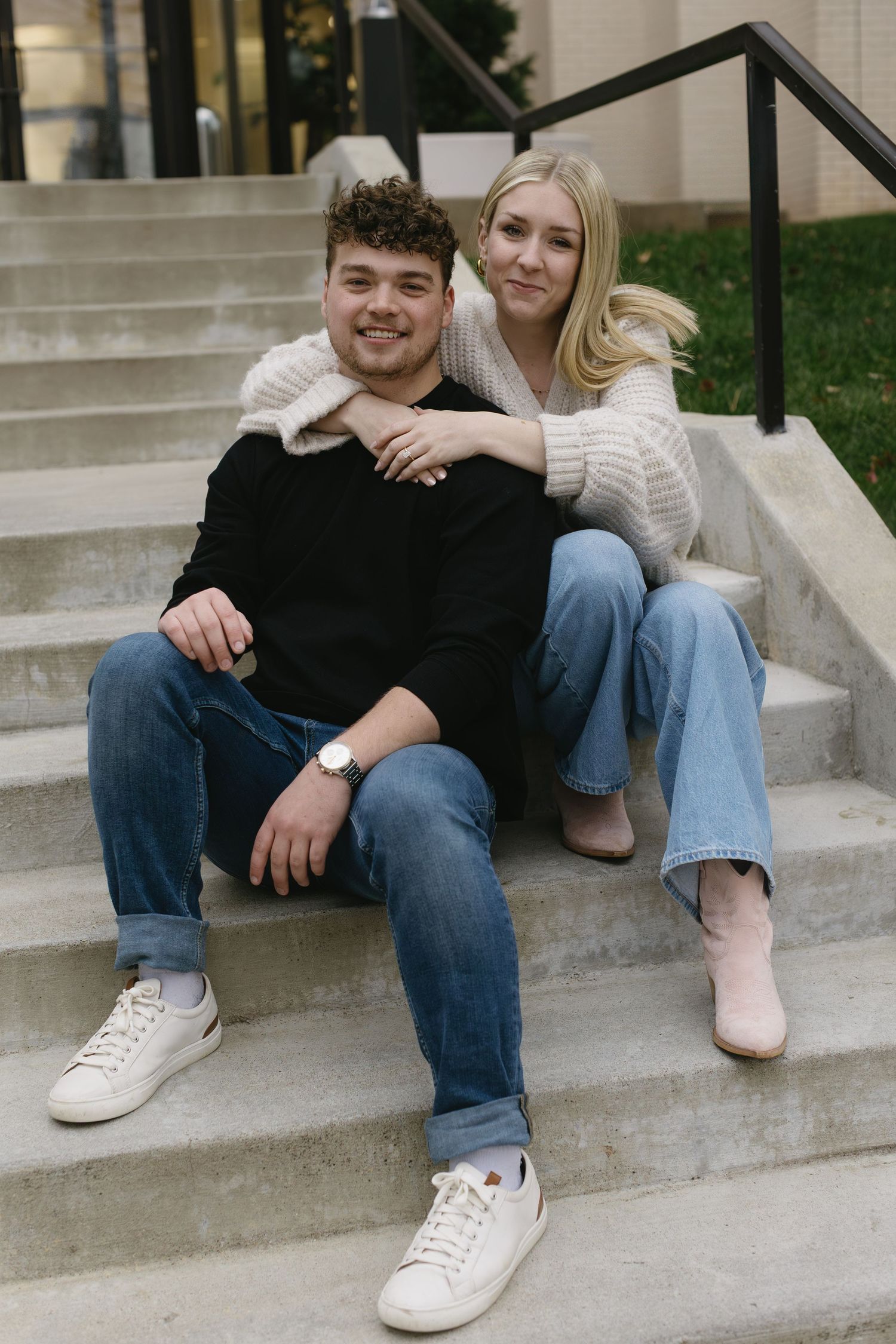 Couple sitting casually on concrete steps wearing coordinated casual outfits.