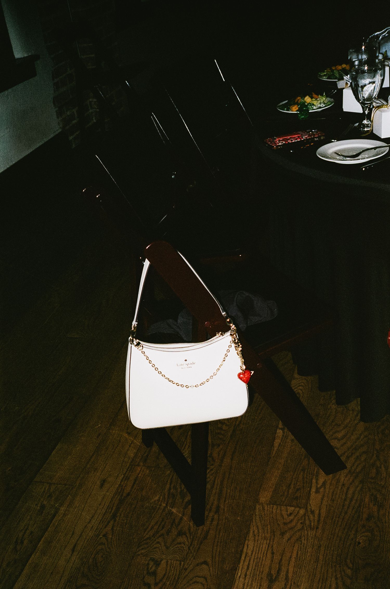 A white evening purse with beaded details sits on a dark wooden floor.