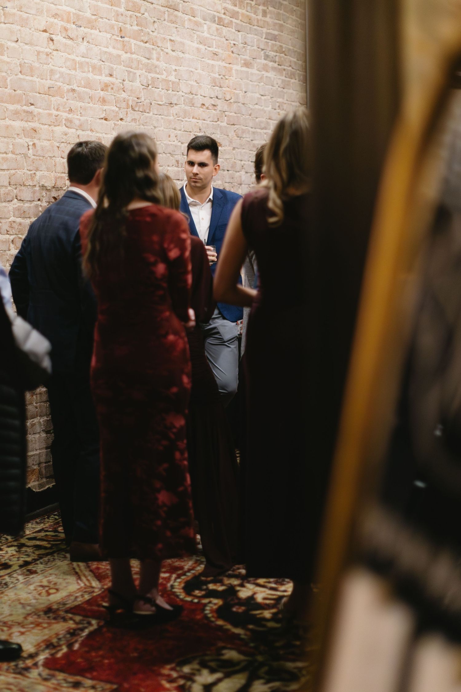 A group of people gathered in front of a brick wall at an indoor event.