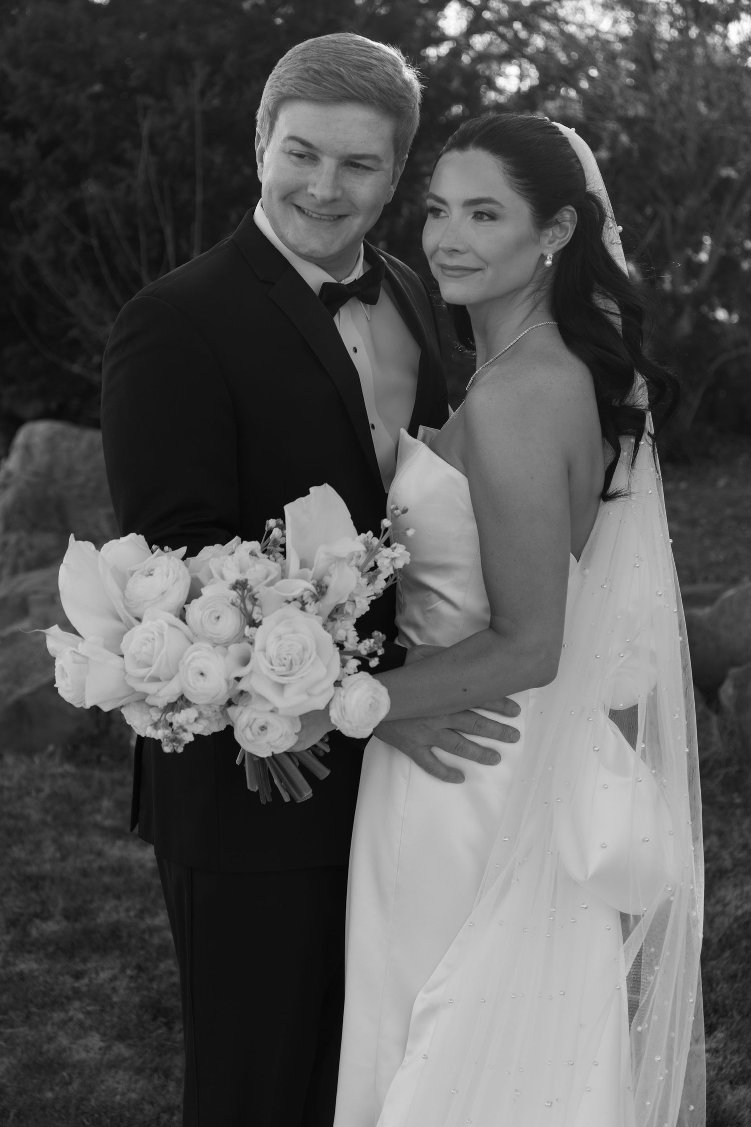 Classic black and white wedding portrait with white roses and formal attire.