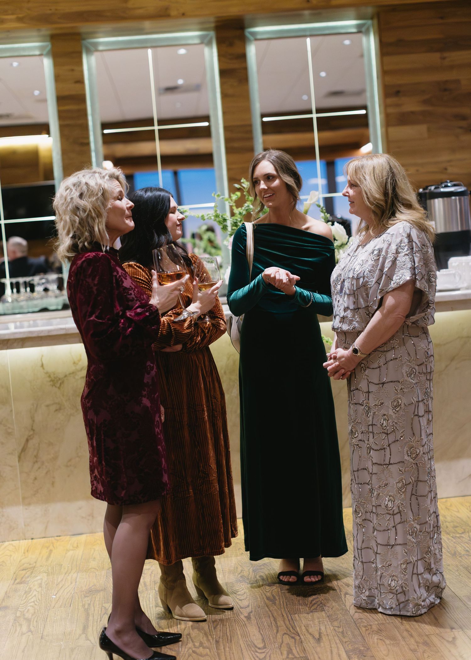 Wedding guests in formal attire mingling at an indoor reception venue.