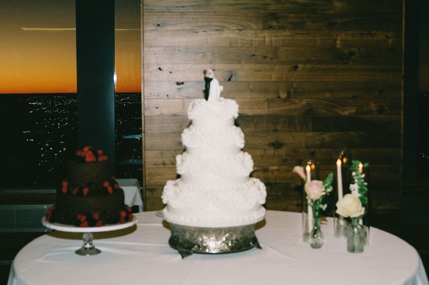 White tiered wedding cake displayed on wooden table with floral decorations.