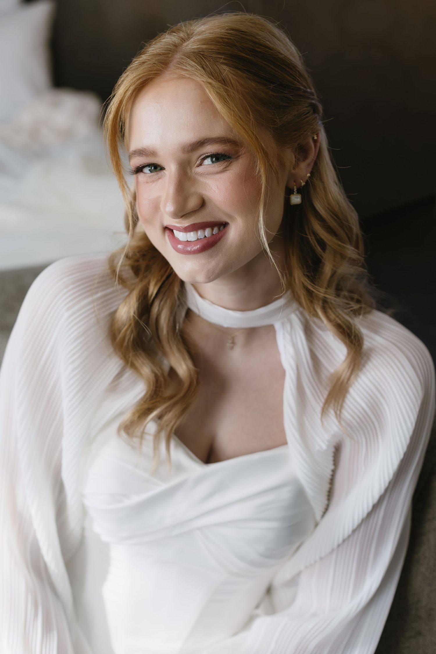 White bridal gown with pleated details shown in artistic portrait style.