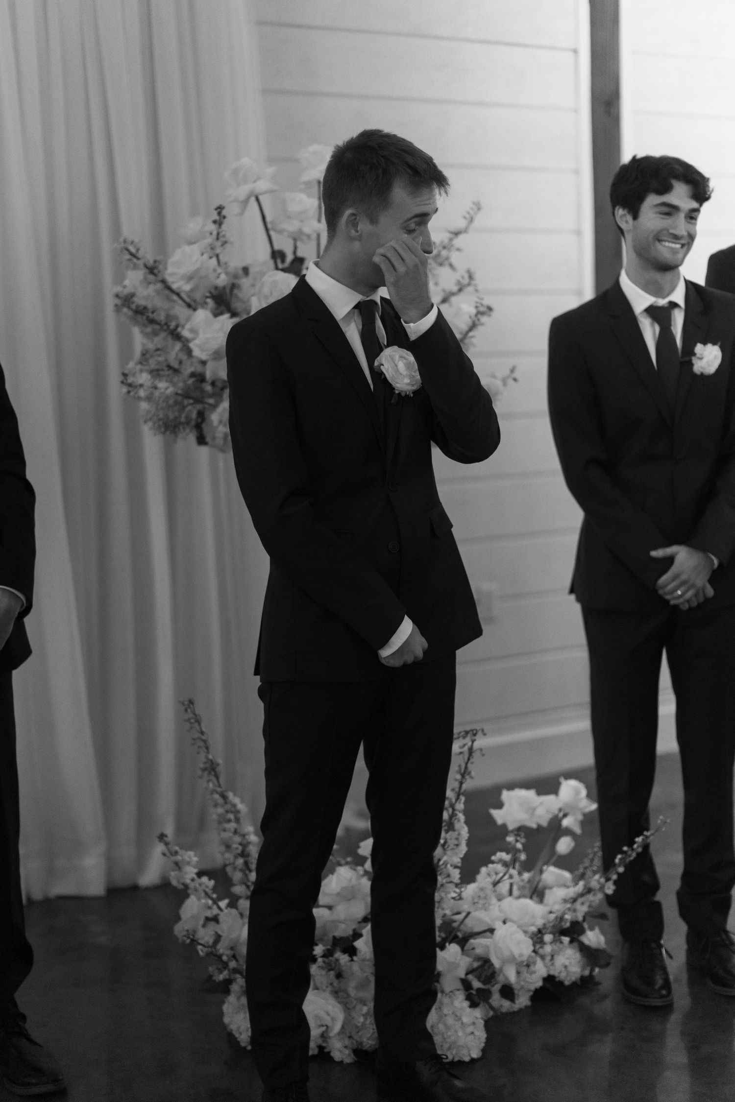 An emotional moment captured in black and white during a wedding ceremony with floral decorations.