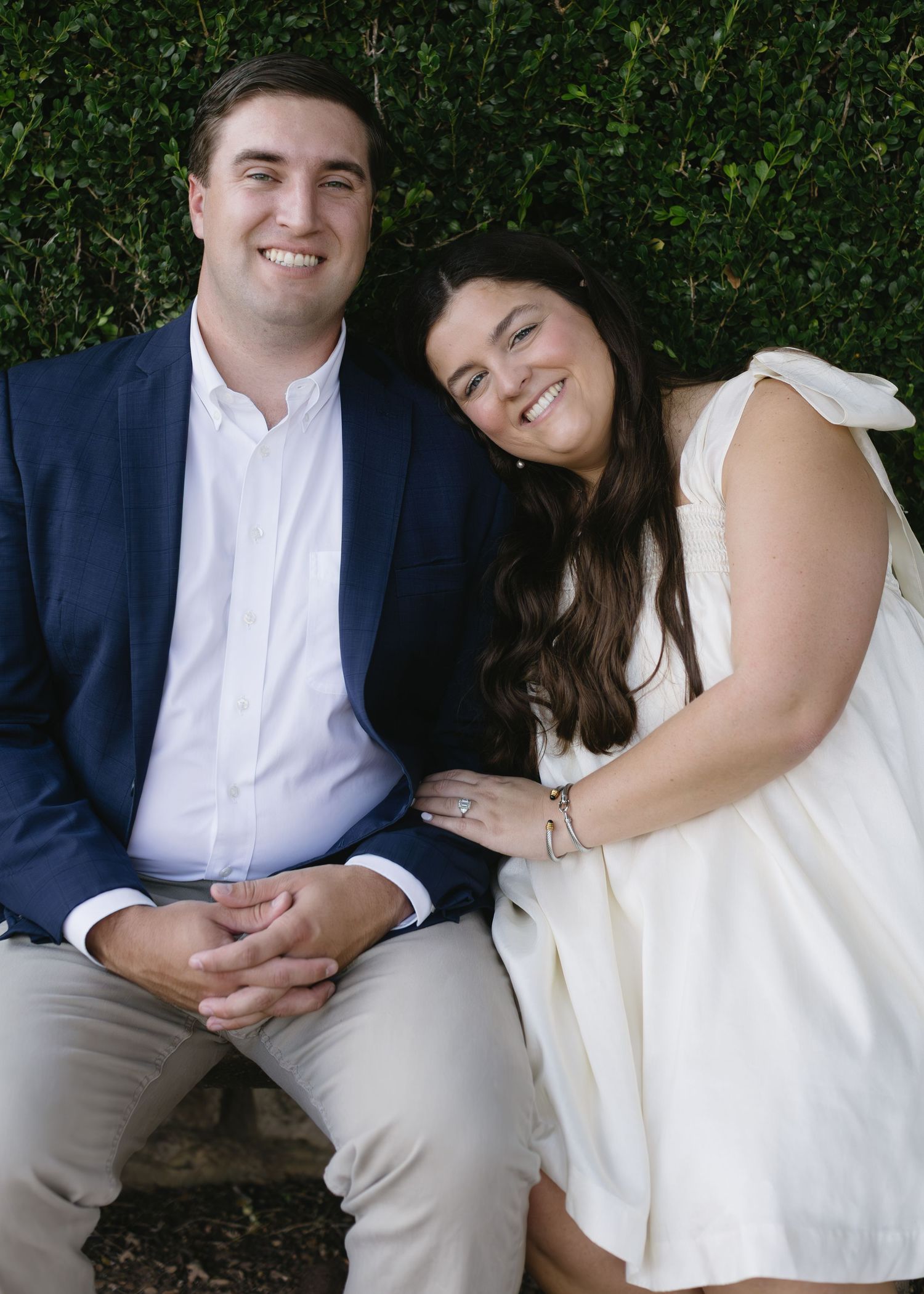 Intimate couple portrait session on a garden bench with lush greenery backdrop.