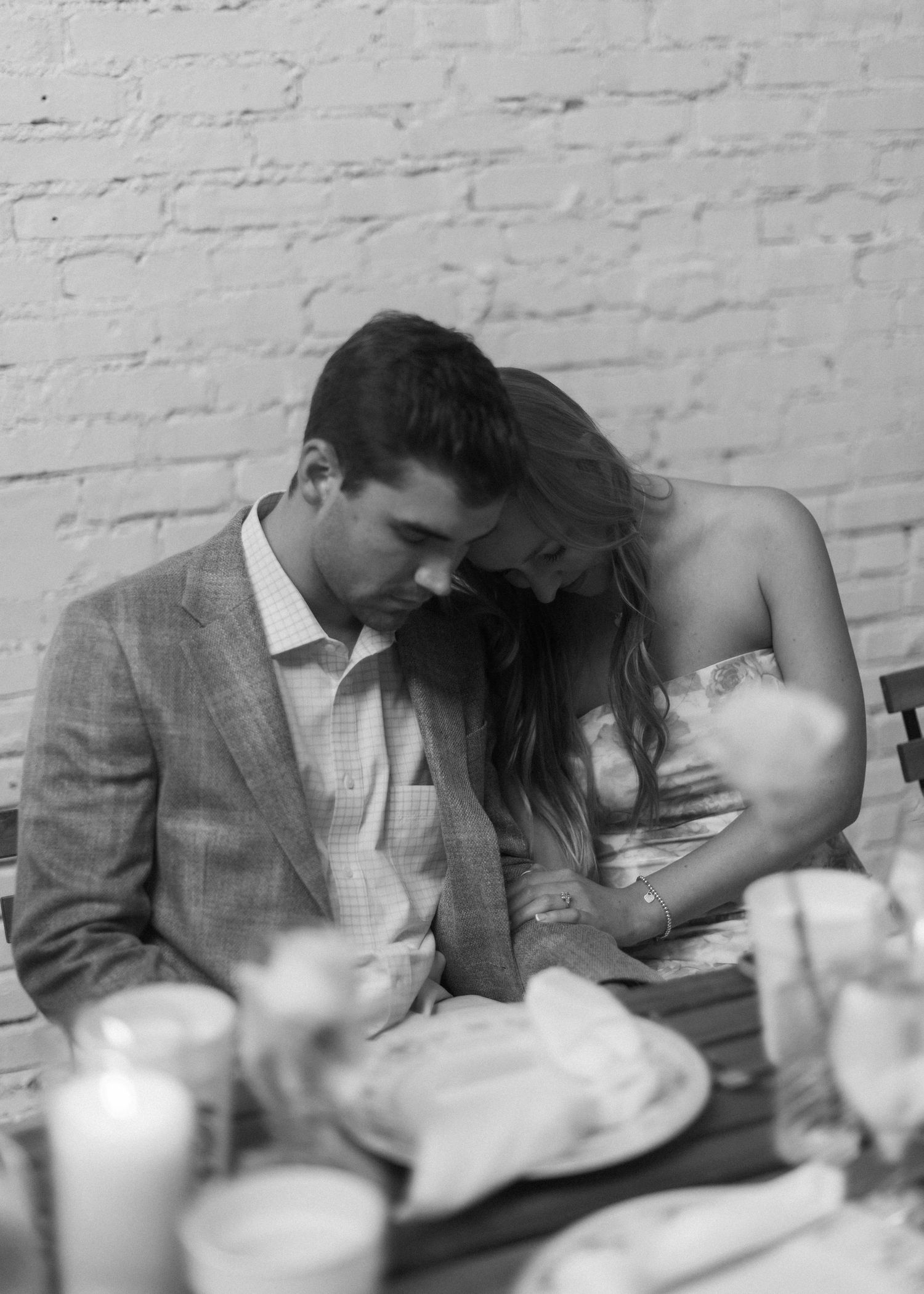 Romantic candlelit restaurant scene with moody lighting and white brick wall background.