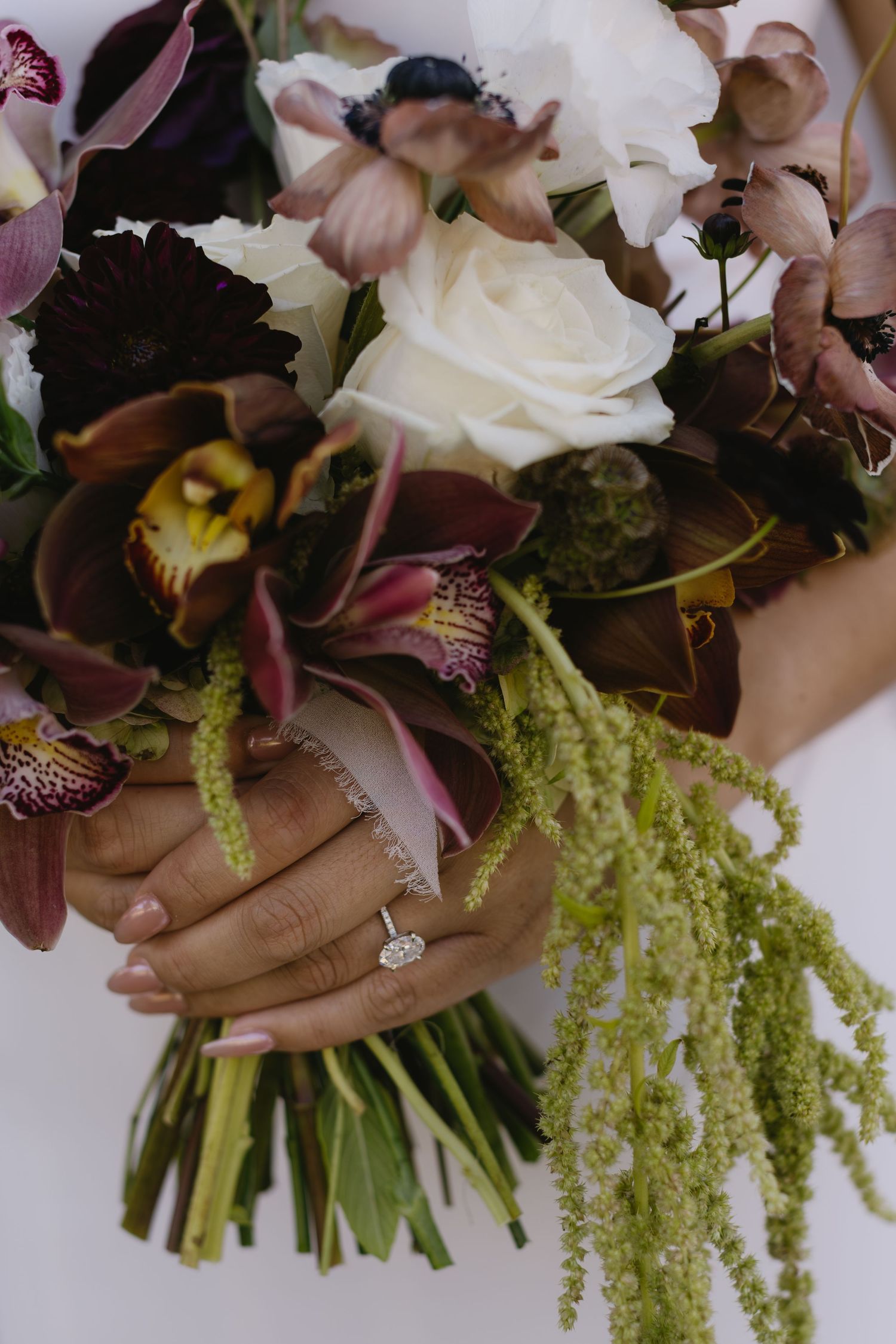 Wedding bouquet featuring purple orchids, white roses and cascading green amaranthus flowers.