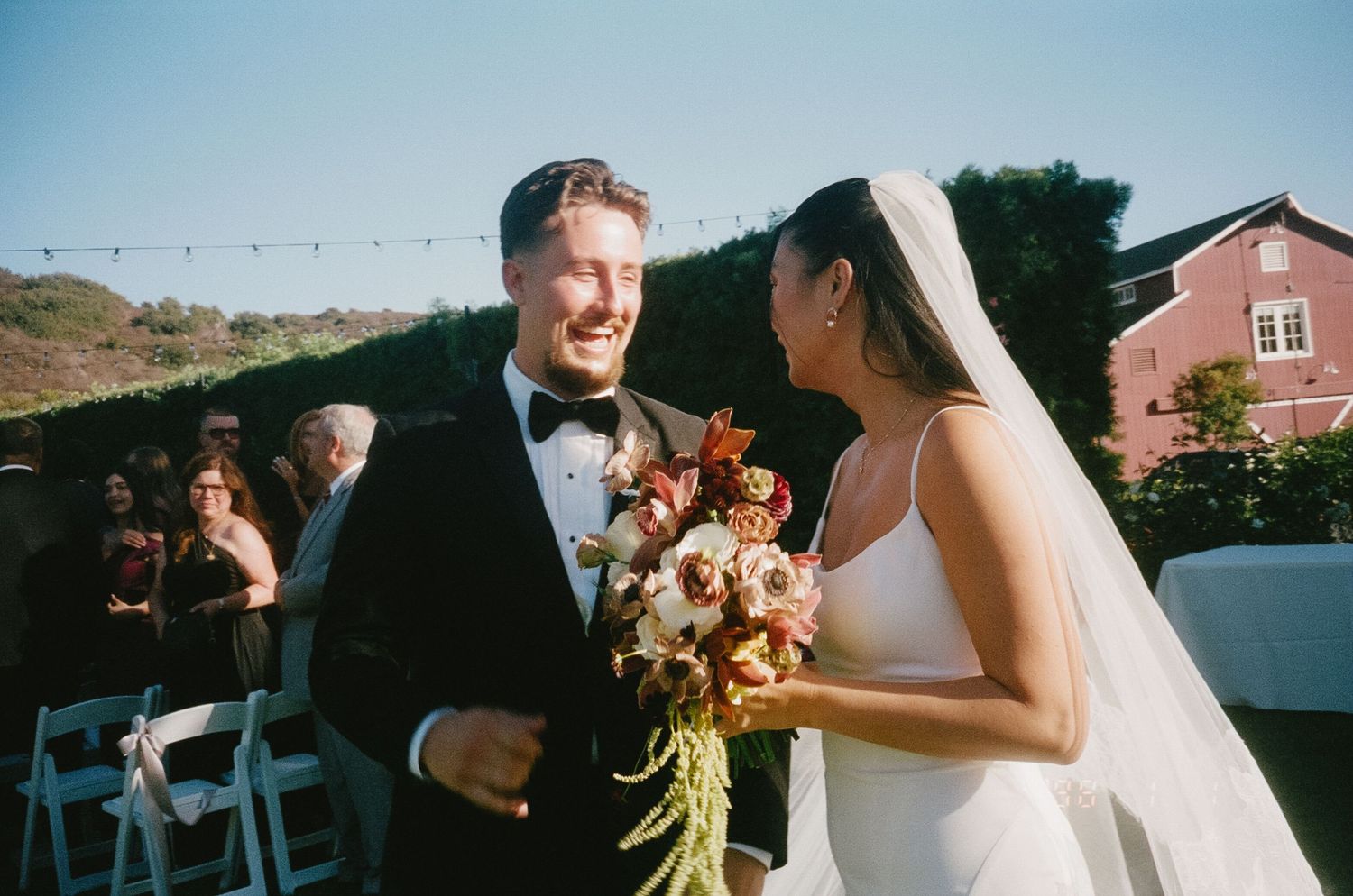 A wedding couple shares intimate moments during their outdoor celebration in golden sunlight.