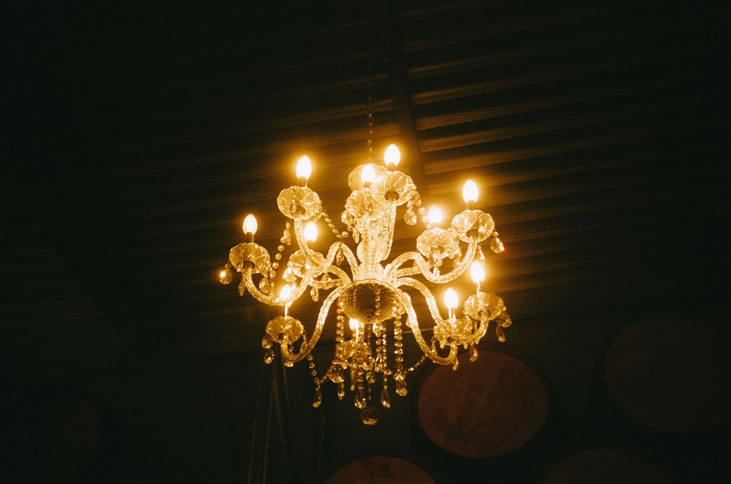Crystal chandelier glowing warmly against dark ceiling creates elegant ambiance.