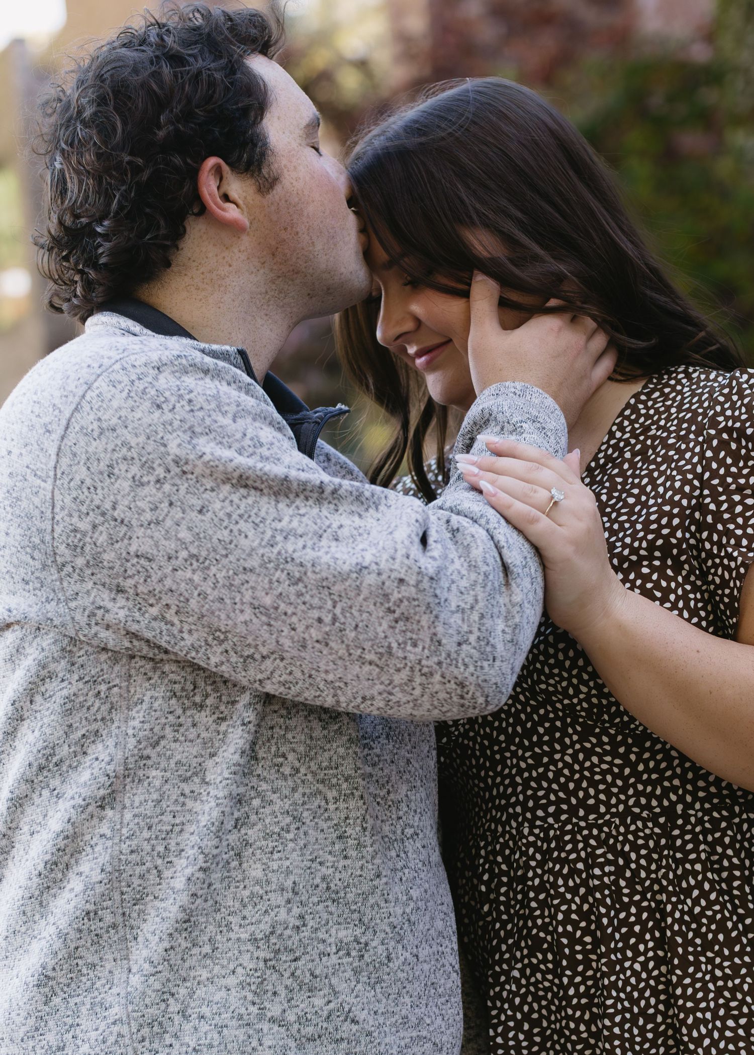 A couple in casual attire shares an intimate moment outdoors.