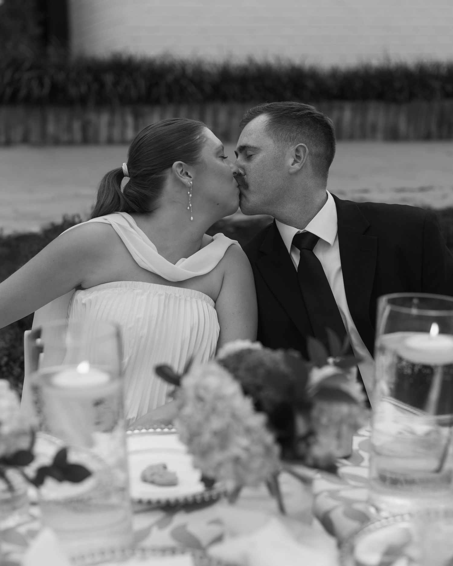 Black and white photo of an intimate wedding reception table with candlelight and floral centerpieces.