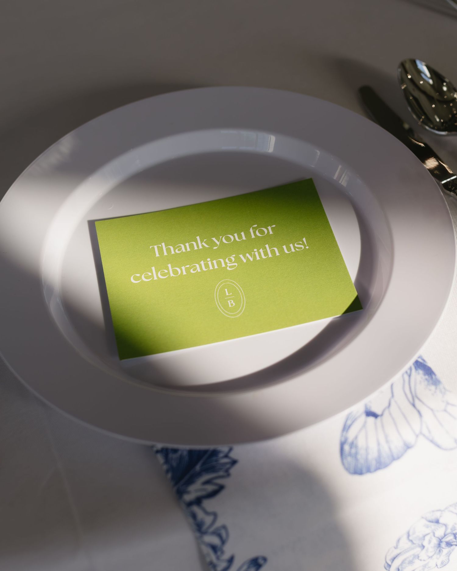 Wedding reception place cards with green accents and thank you messages on white plates.