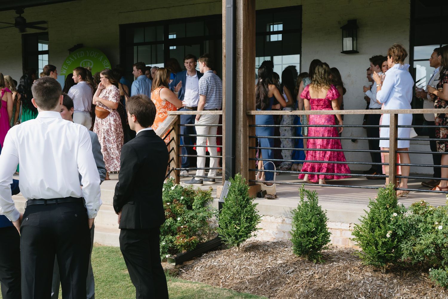 Large group of wedding guests gathered outside a covered patio area.