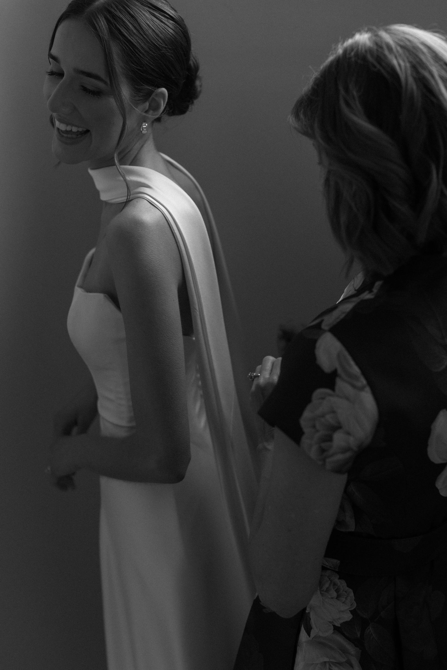Black and white candid moments show a bride getting ready in her wedding dress.