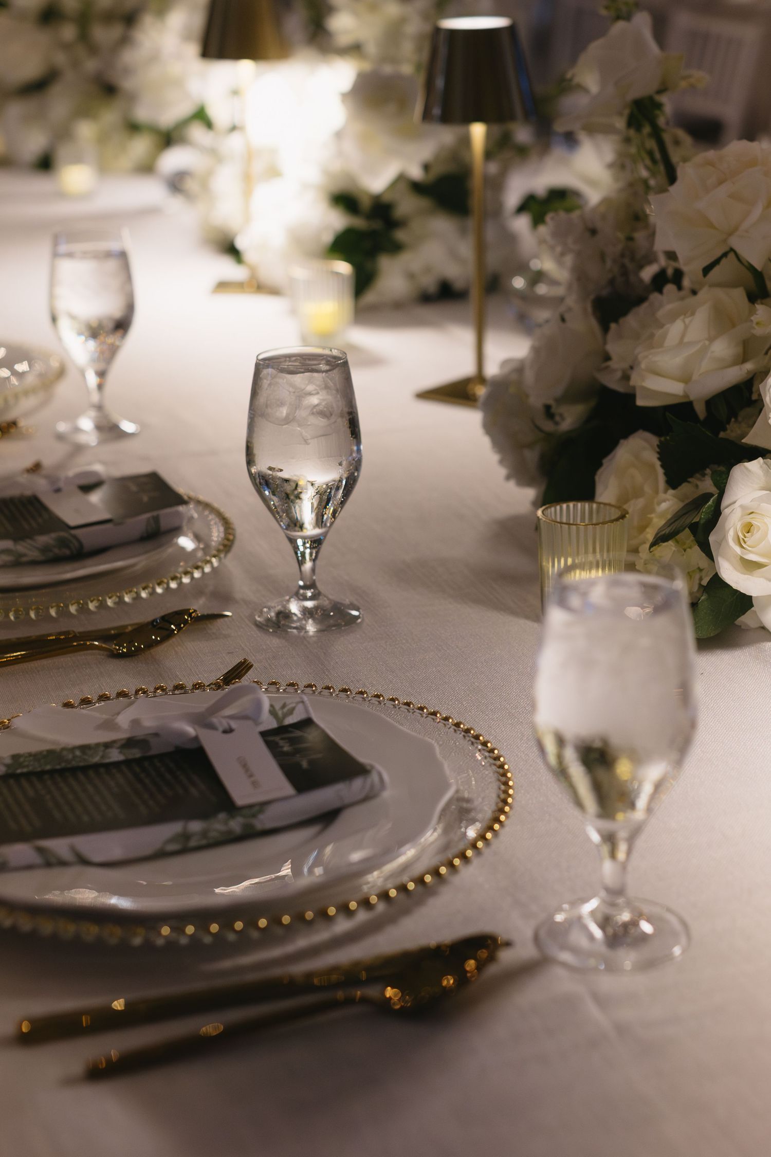 Close-up of luxurious place settings with gold-rimmed charger plates and crystal stemware.