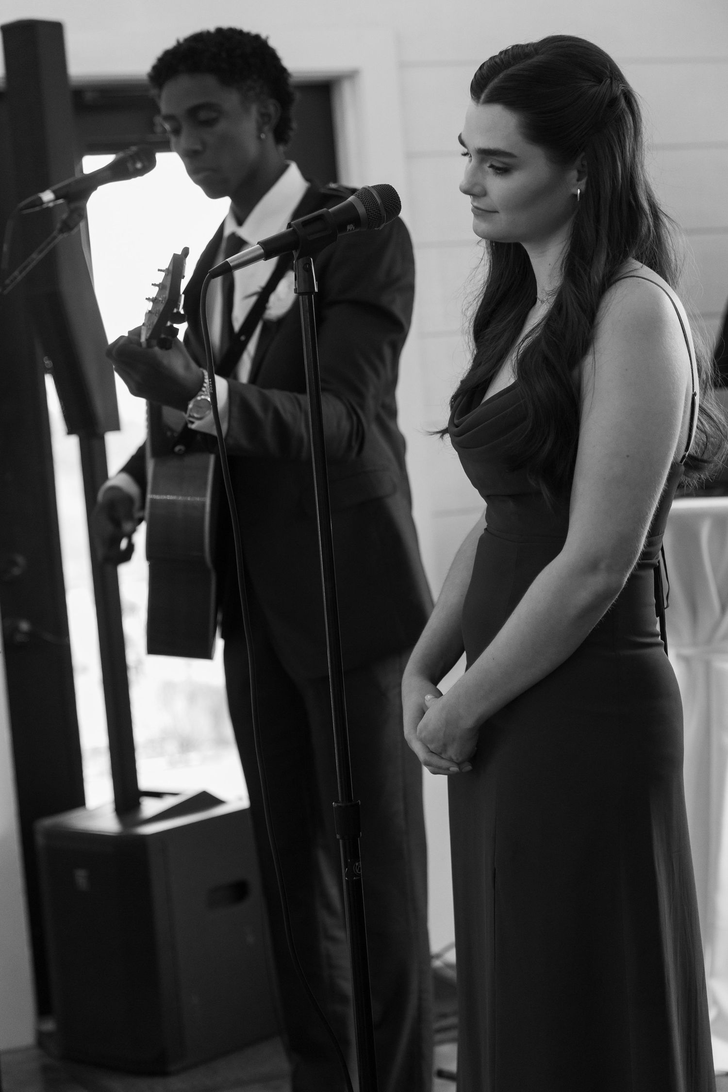 Row of bridesmaids in elegant black dresses standing together during wedding ceremony.
