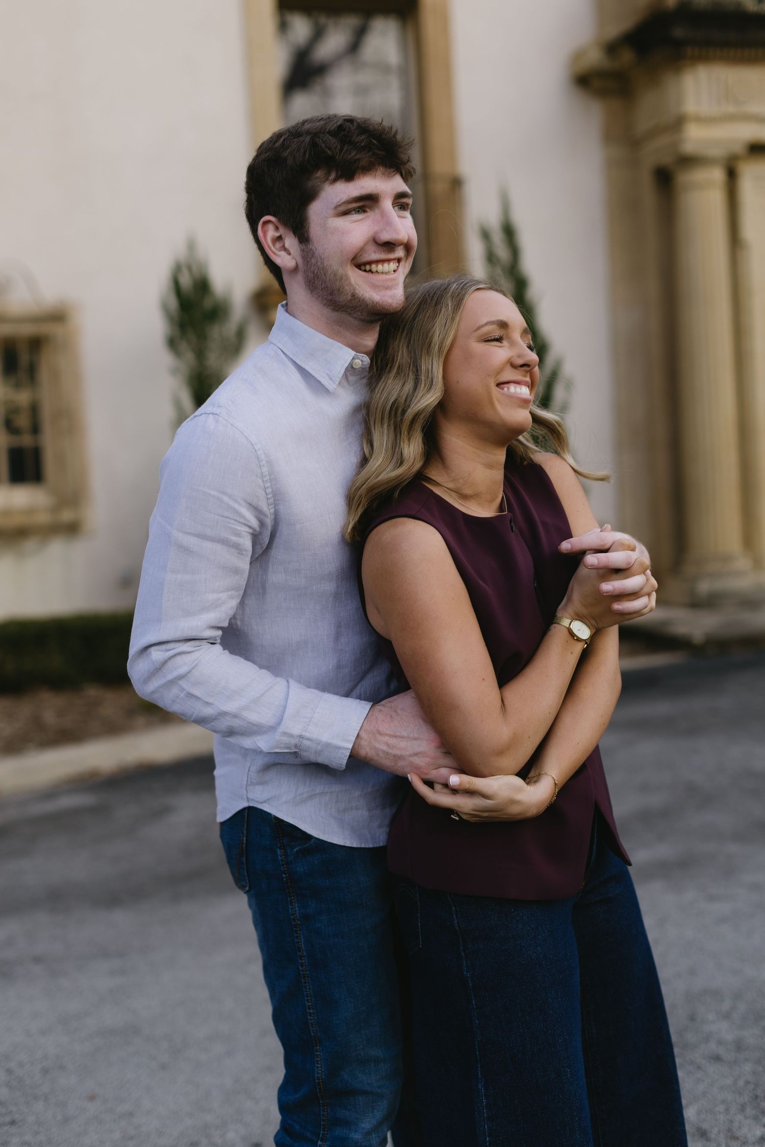 A couple sharing a joyful moment together while embracing, with the person in burgundy laughing candidly.