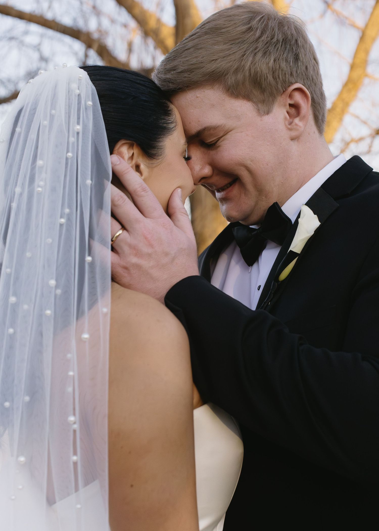 Romantic wedding couple embracing during sunset photo session outdoors.