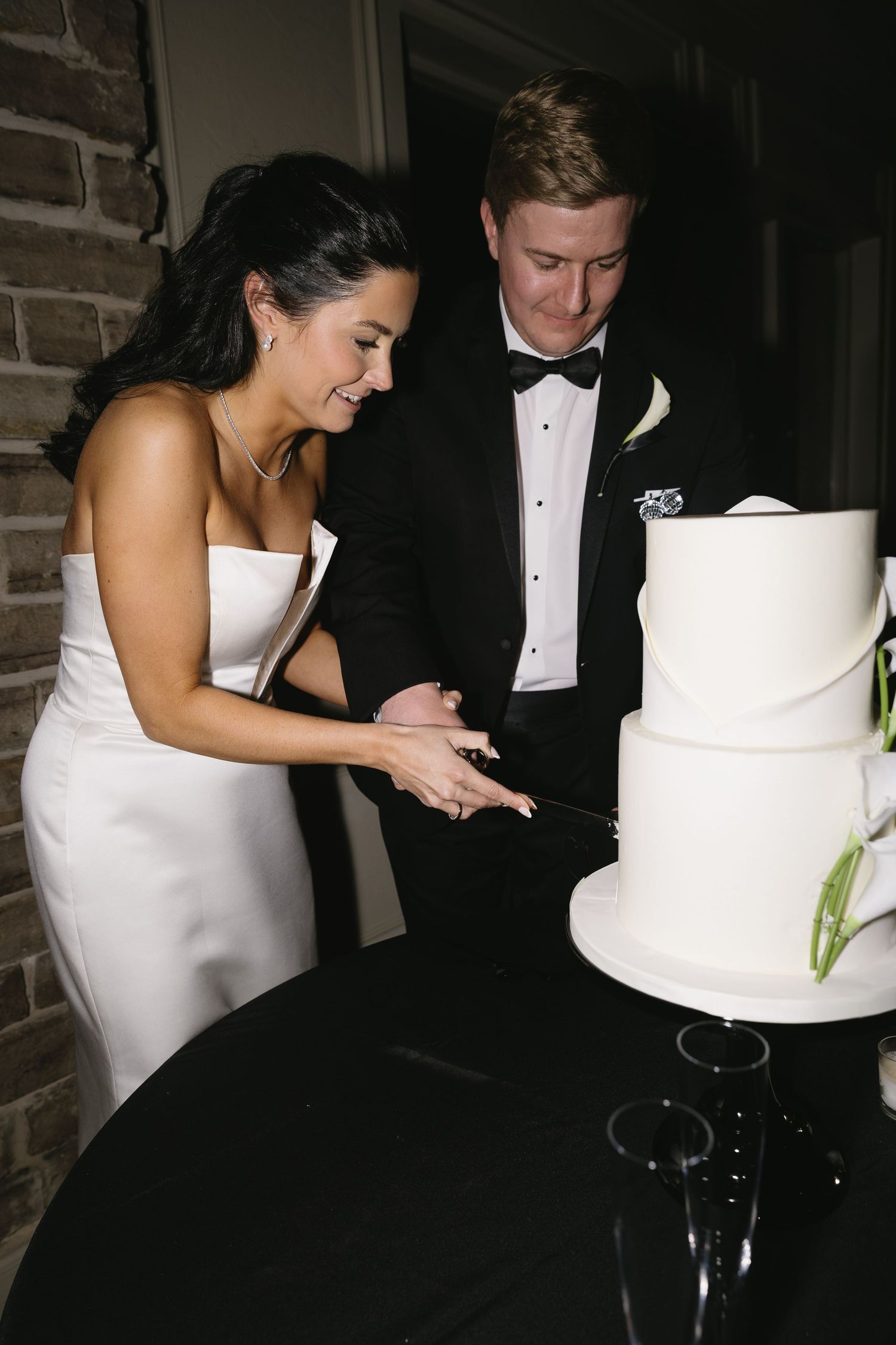 A couple cuts their elegant white wedding cake together at their reception.