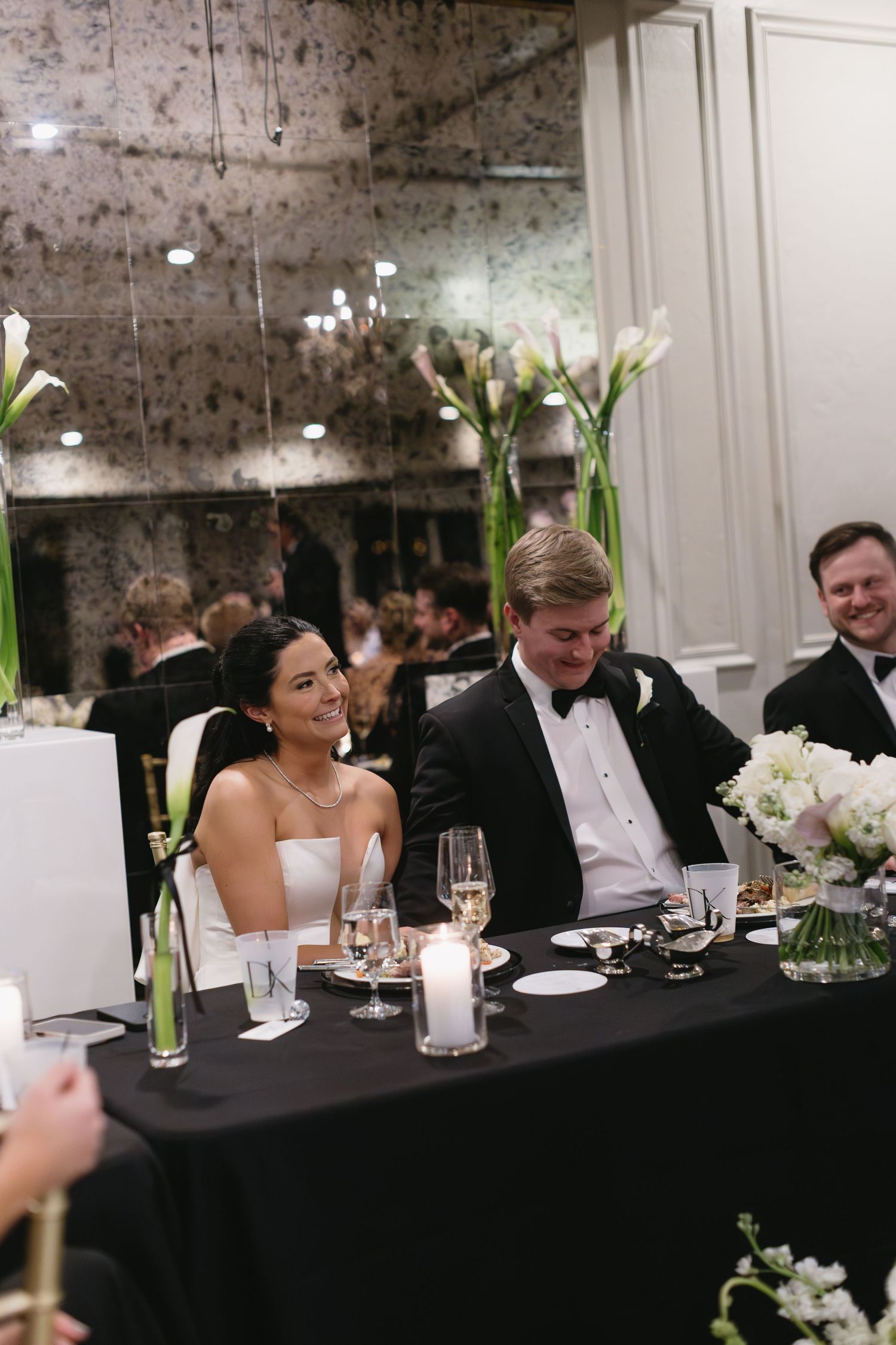 Elegant wedding reception dinner table decorated with white flowers and tall vases in a sophisticated venue.