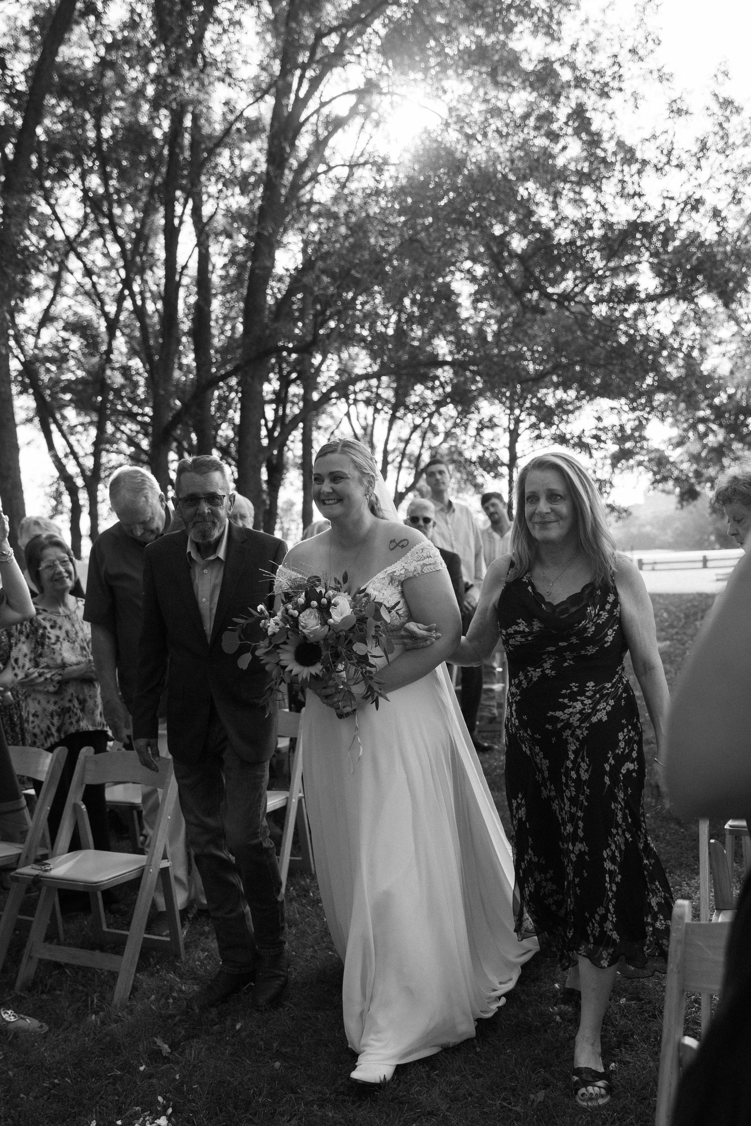 Wedding celebration in progress with guests gathered on grassy hillside.