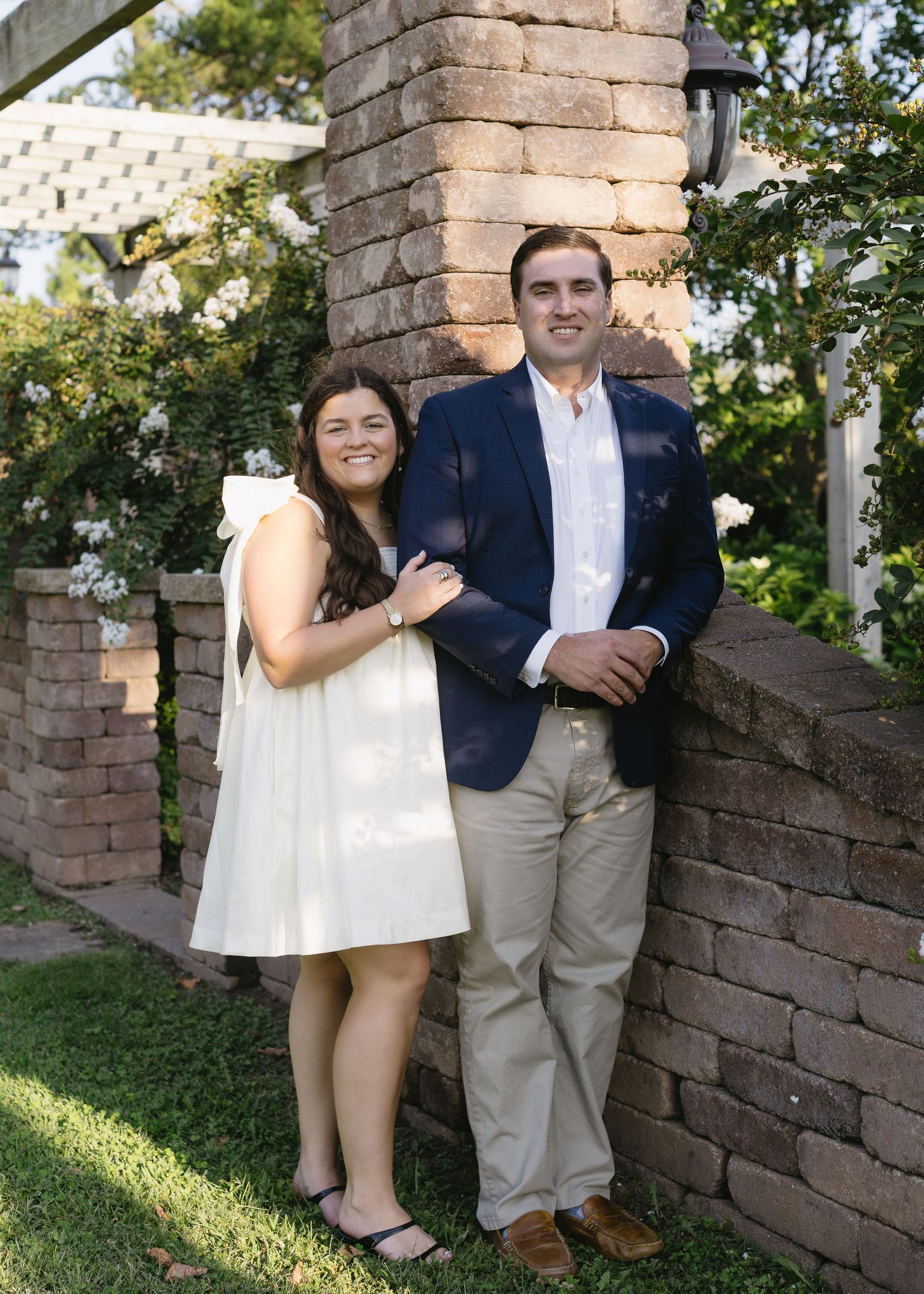 Romantic couple photos taken against a rustic stone wall during a sunny outdoor photoshoot.