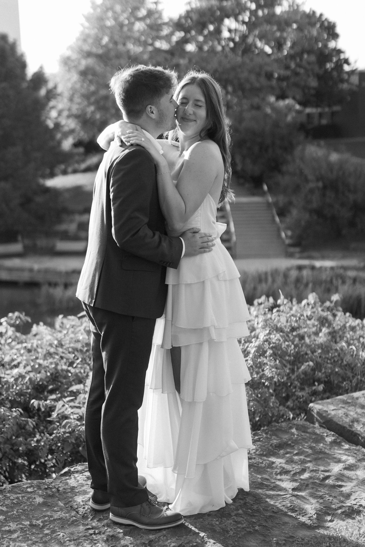 A couple shares tender moments together in a garden setting with blooming flowers.