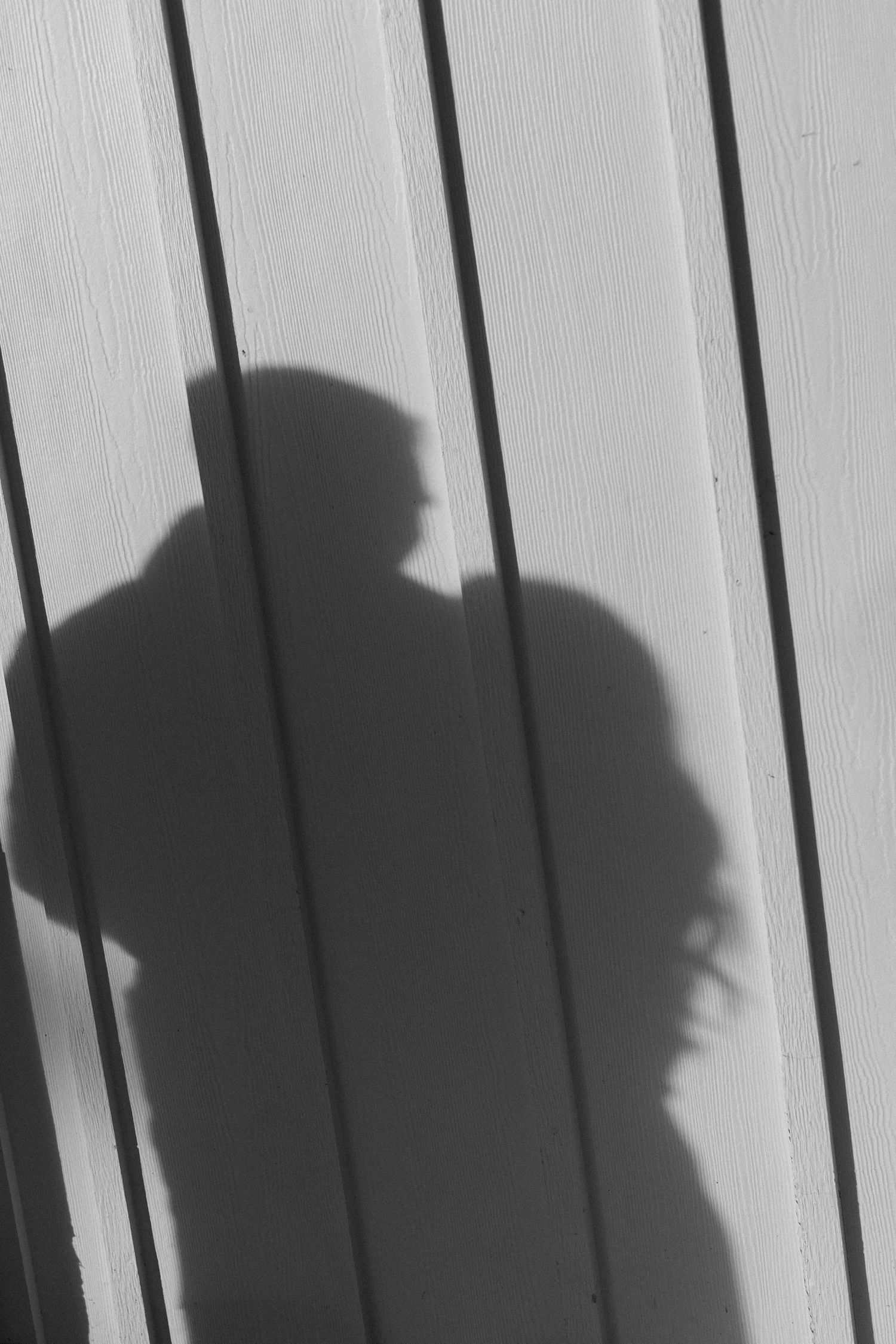 Shadow silhouettes of two people cast on white wooden panels showing an intimate moment.