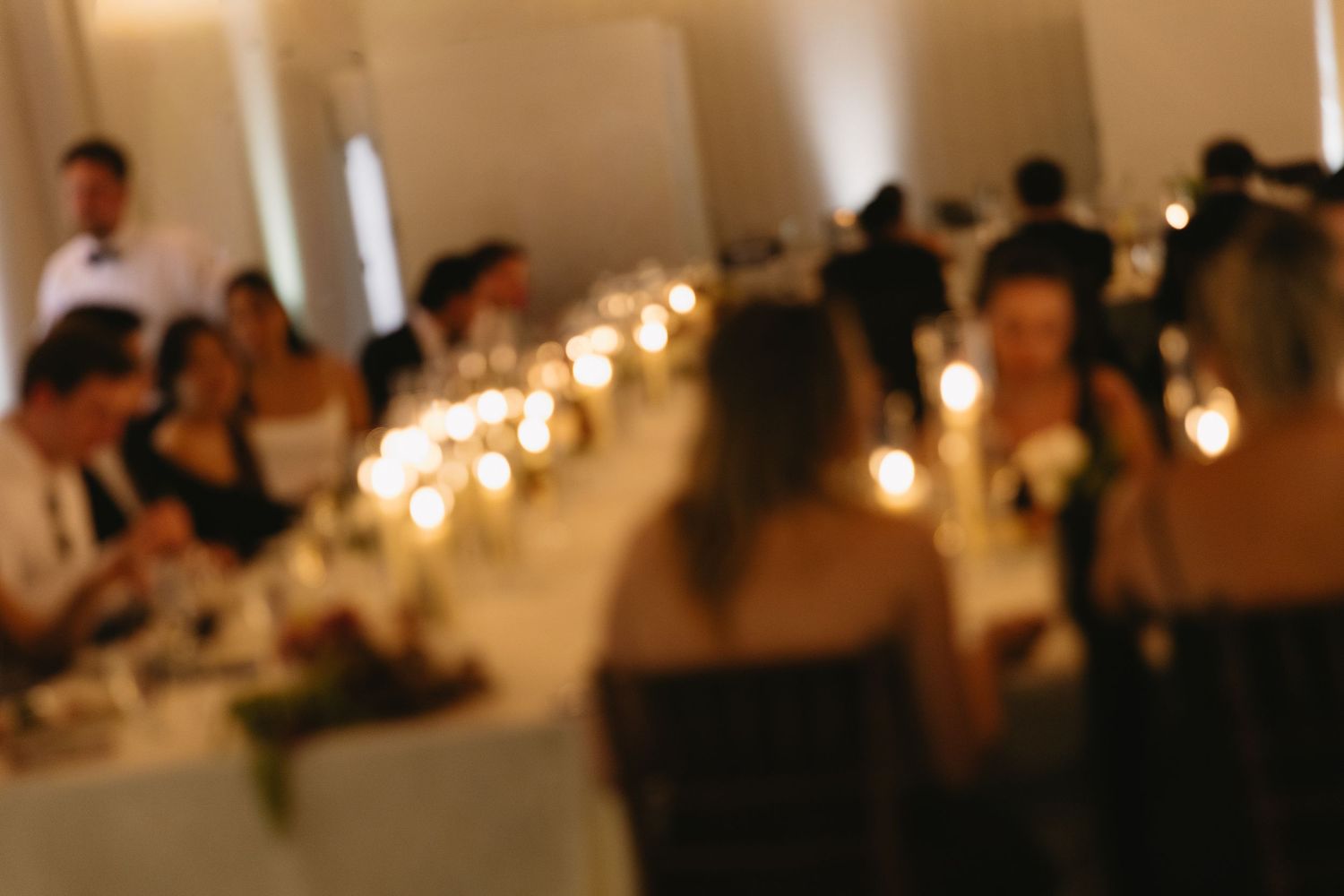 Soft focus wedding reception venue with ambient lighting and decorated tables.