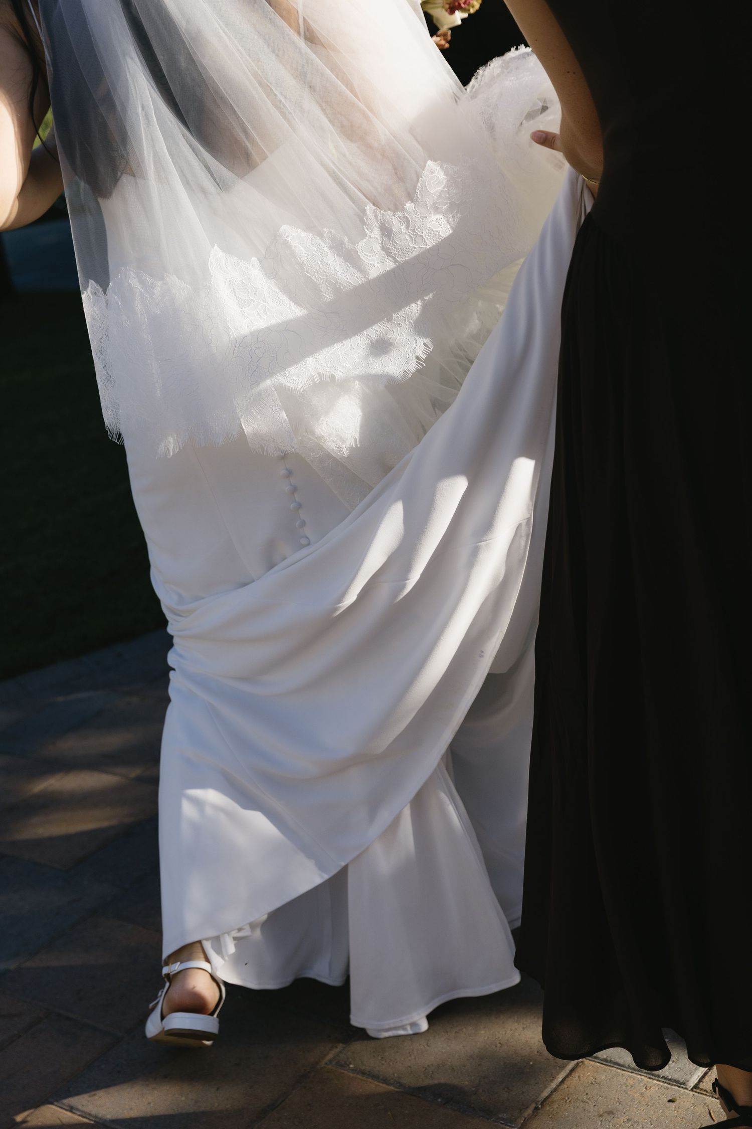Detail shots of white wedding dress and shoes during outdoor celebration.