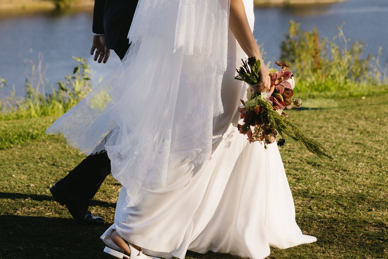 Flowing white wedding dress captured in motion against a waterfront backdrop.